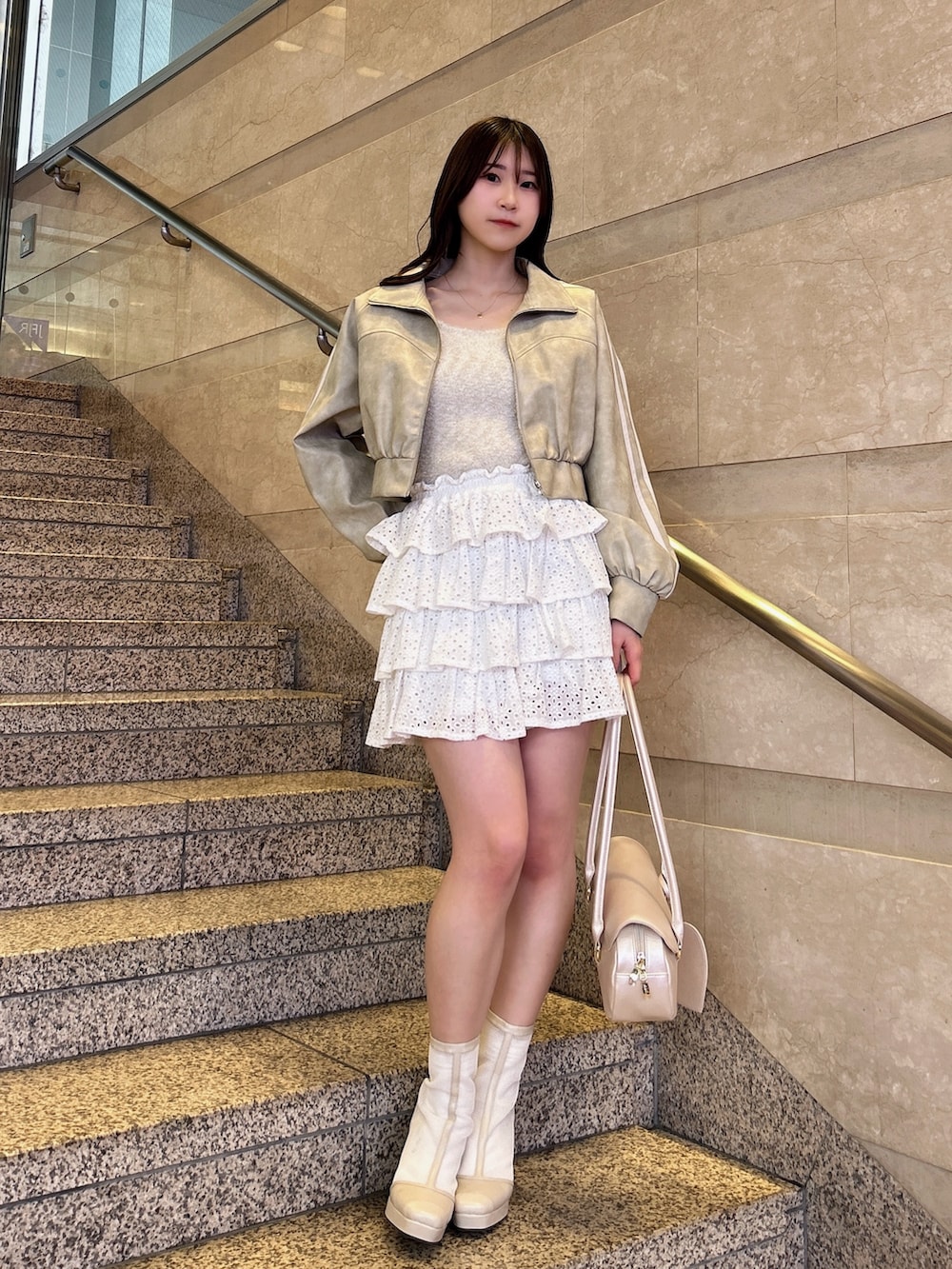 グレー系のブルゾン、ベージュ系のキャミソール、ホワイト系のスカートを着用したレディースの春コーディネートの2枚目の写真