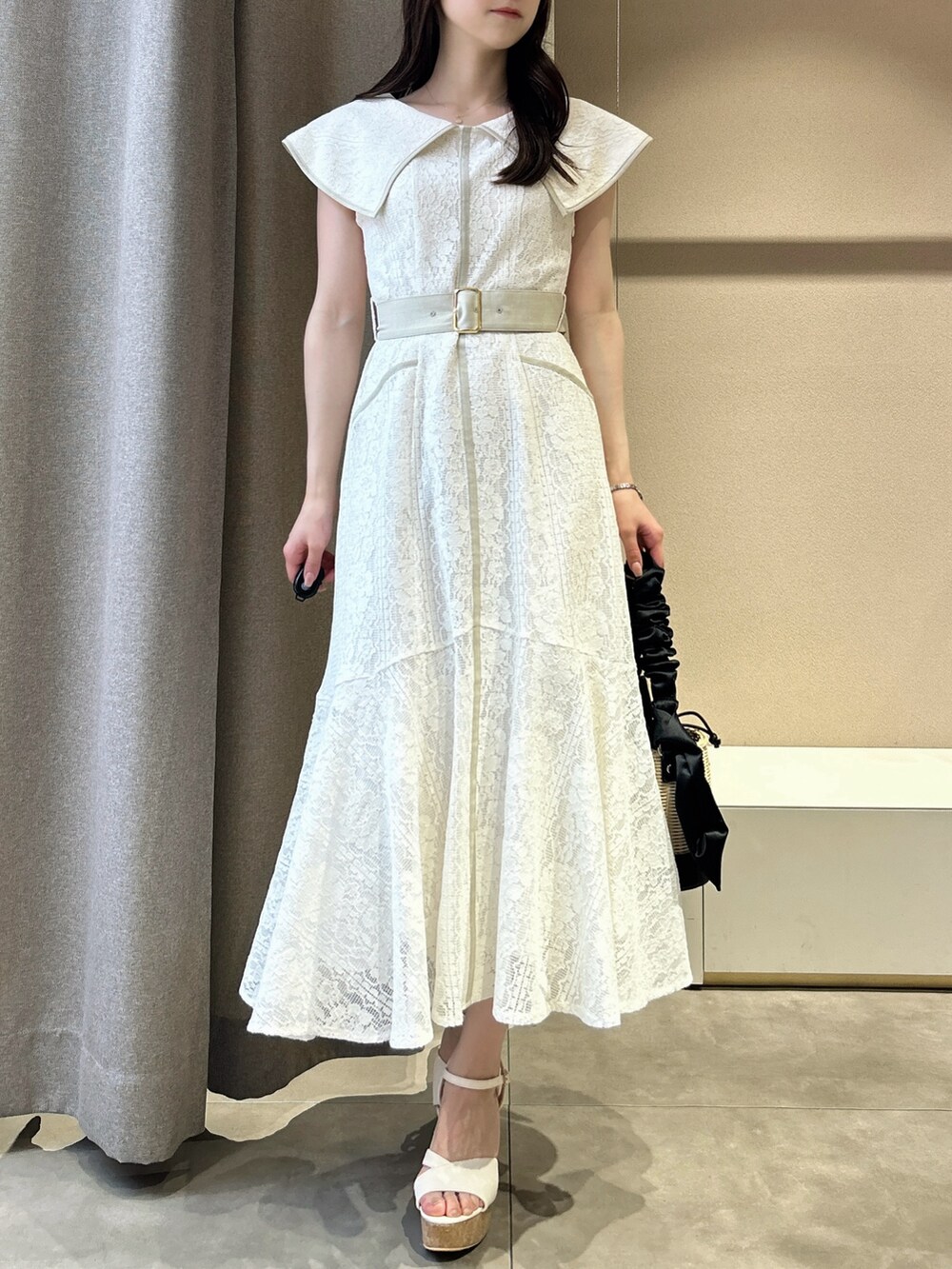 ホワイト系のワンピース、ホワイト系のサンダル、ブラック系のかごバッグを着用したレディースの夏コーディネートの3枚目の写真