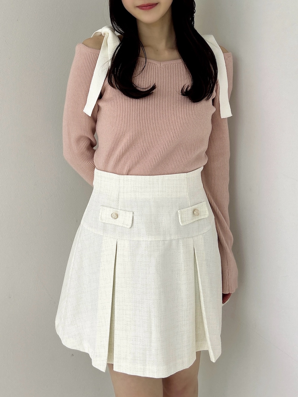 ピンク系のニット/セーター、ホワイト系のスカート、ホワイト系のブーツを着用したレディースの冬コーディネートの6枚目の写真