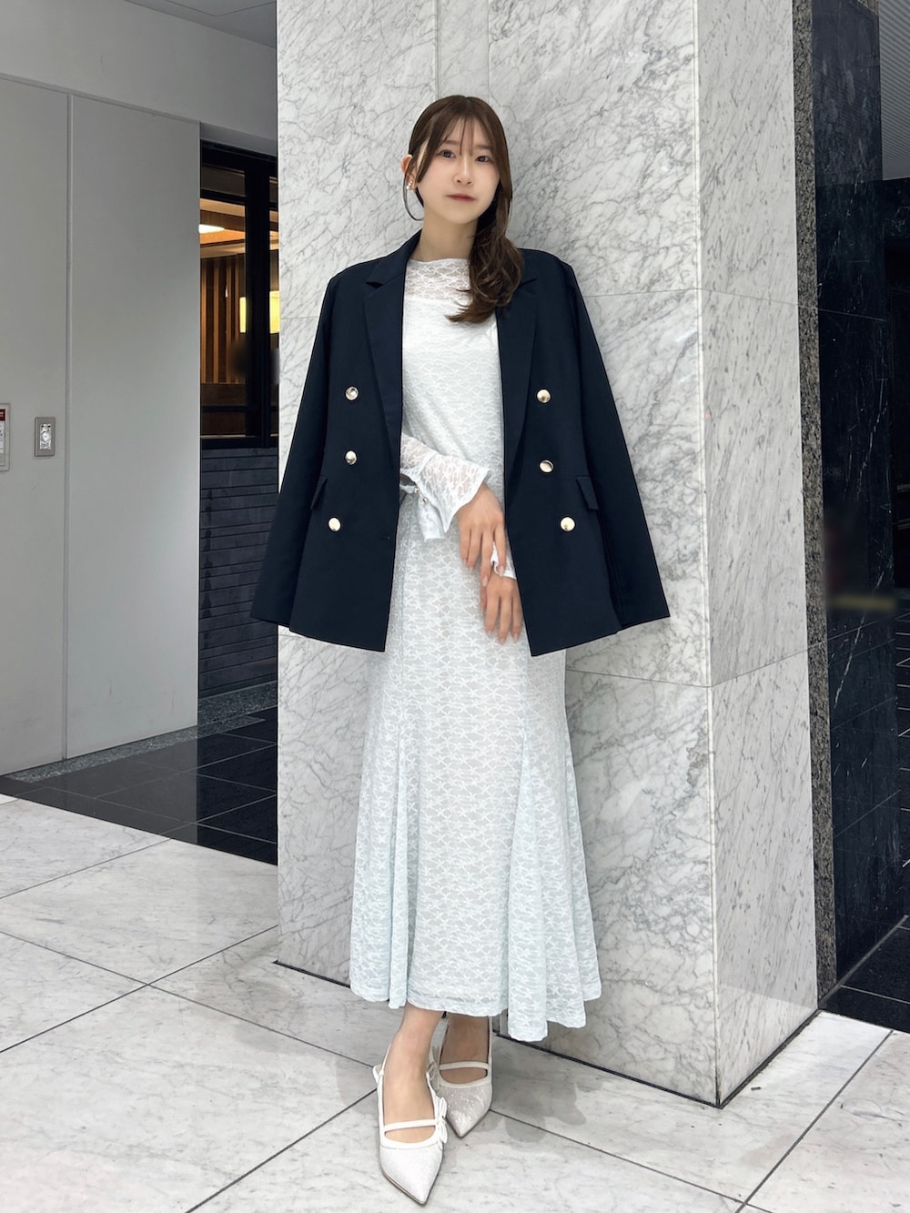 ブルー系のテーラードジャケット、ブルー系のワンピース、ホワイト系のパンプスを着用したレディースの春コーディネートの2枚目の写真