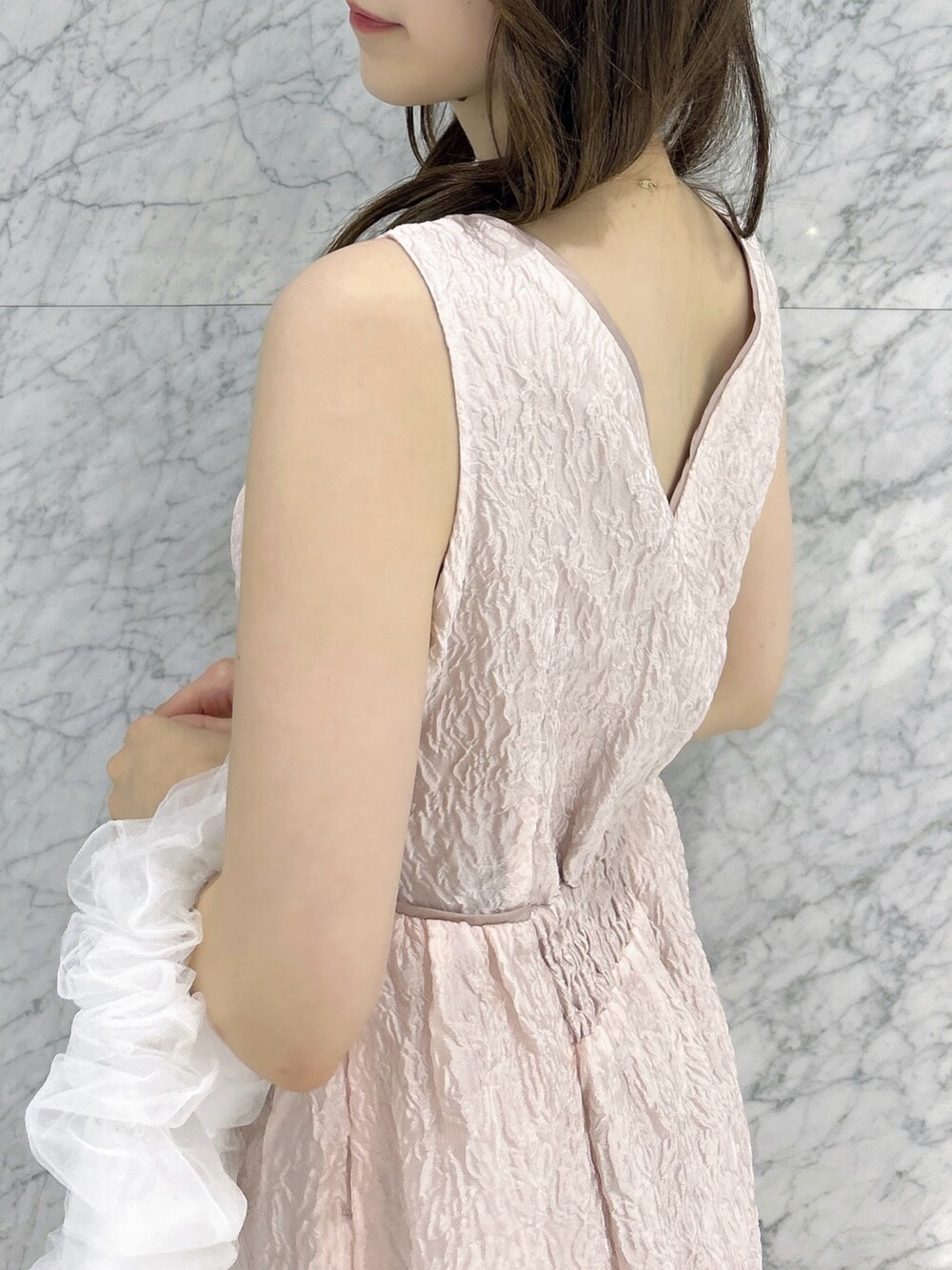 ホワイト系のパンプス、ホワイト系のハンドバッグ、ピンク系のドレスを着用したレディースの夏コーディネートの7枚目の写真