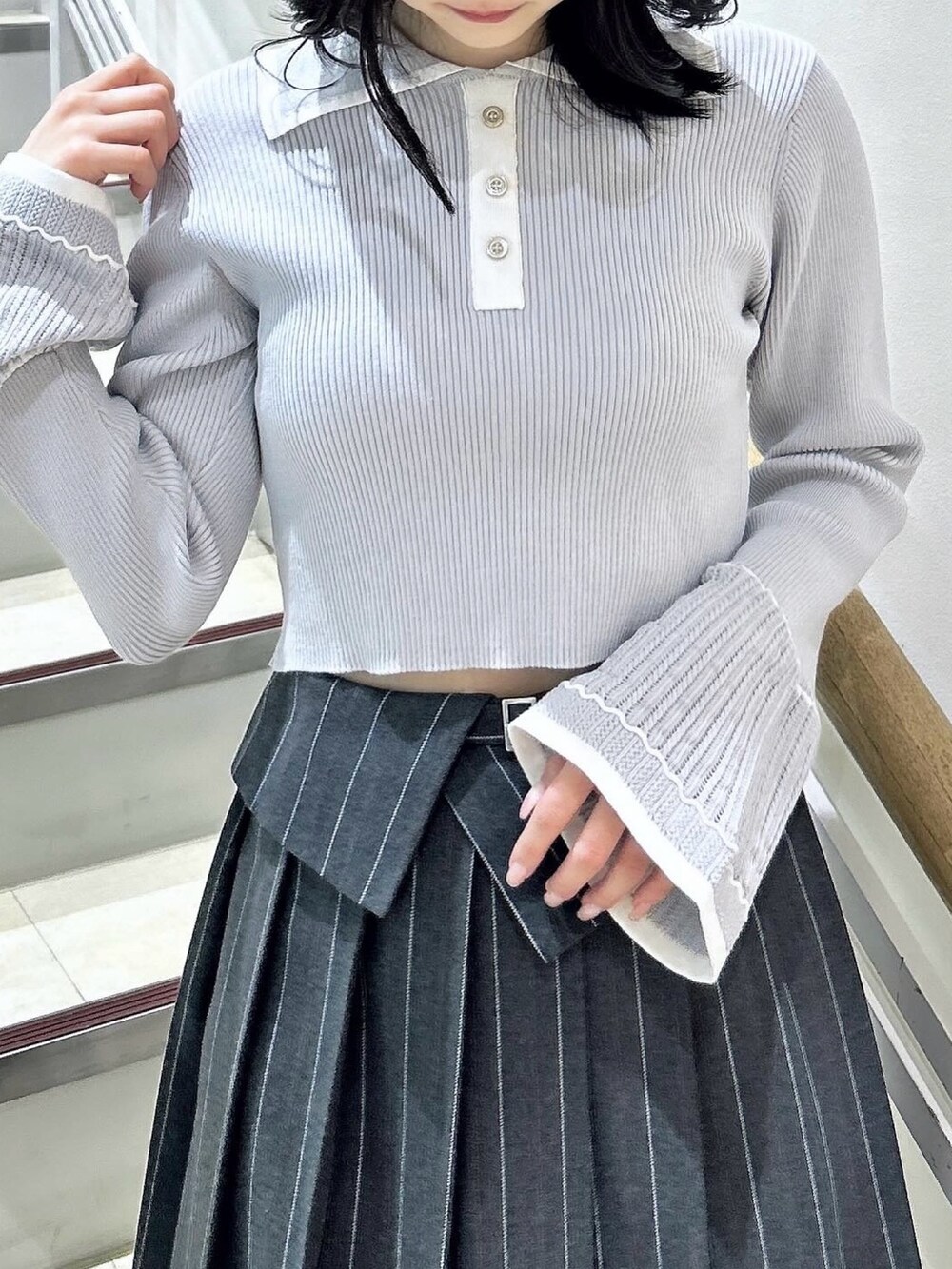 グレー系のニット/セーター、グレー系のスカート、ブラック系のブーツを着用したレディースの冬コーディネートの7枚目の写真