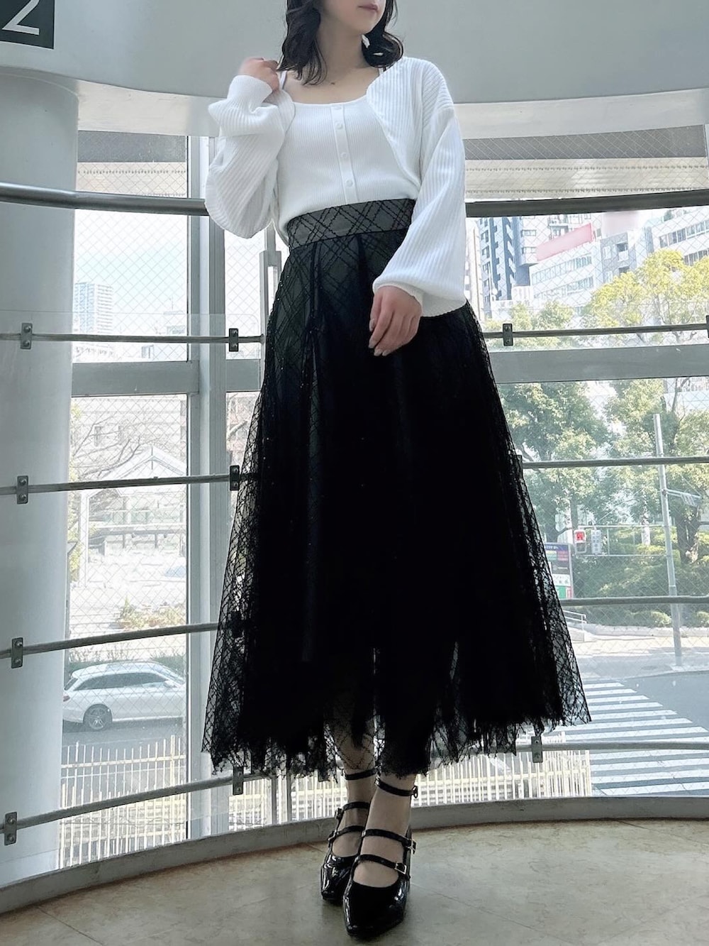 ホワイト系のアンサンブル、ブラック系のスカート、ブラック系のパンプスを着用したレディースの春コーディネートの4枚目の写真