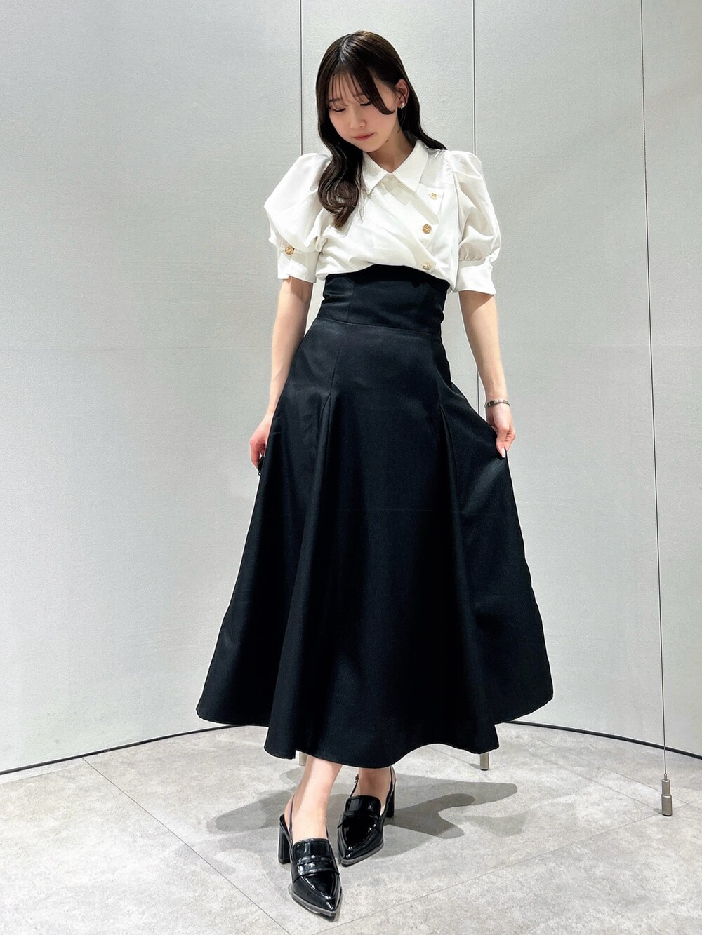 ホワイト系のシャツ/ブラウス、ブラック系のスカート、ブラック系のローファーを着用したレディースの春コーディネートの2枚目の写真