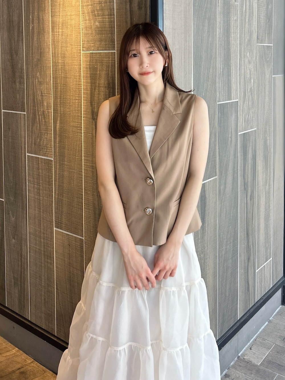 ブラウン系のベスト、ホワイト系のTシャツ/カットソー、ベージュ系のスカートを着用したレディースの秋コーディネートの6枚目の写真