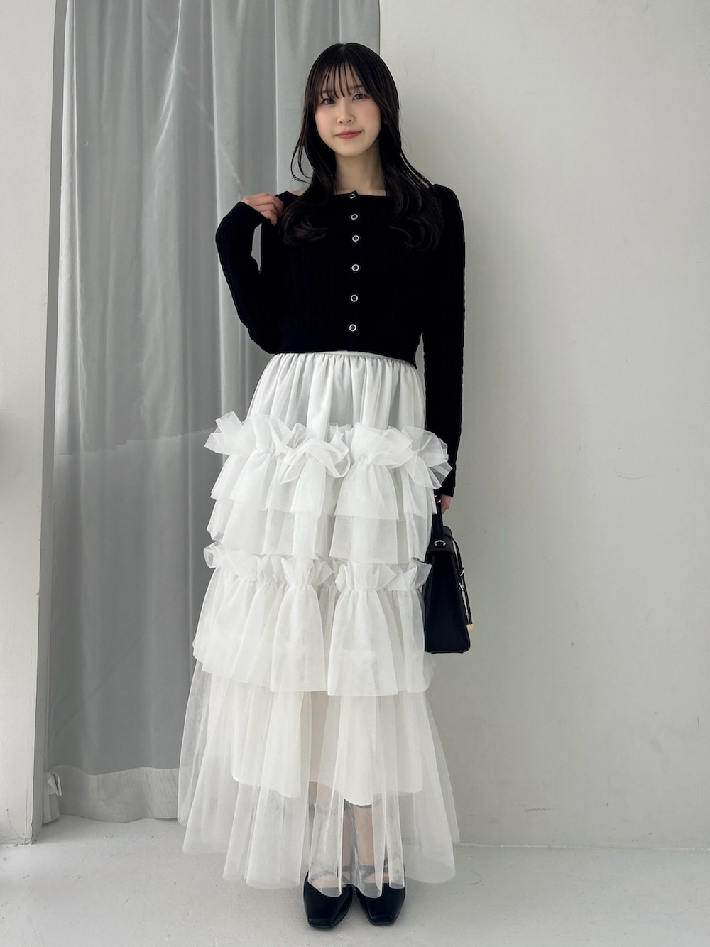 ブラック系のニット/セーター、ホワイト系のスカート、ブラック系のサンダルを着用したレディースの冬コーディネートの5枚目の写真