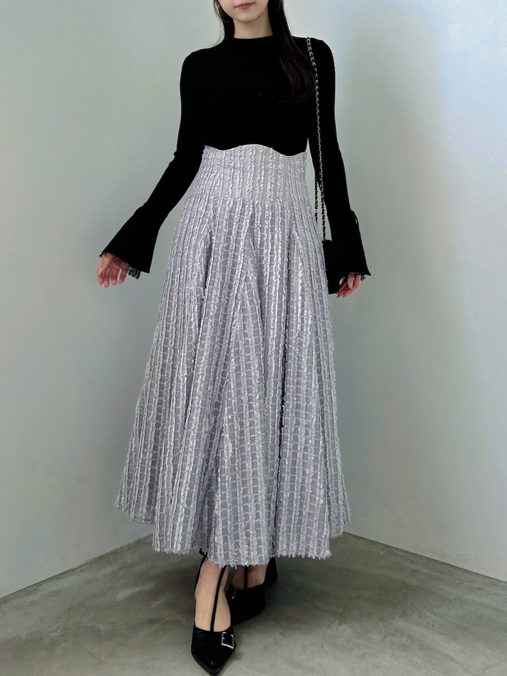 ブラック系のニット/セーター、グレー系のスカート、ブラック系のパンプスを着用したレディースの秋コーディネートの2枚目の写真