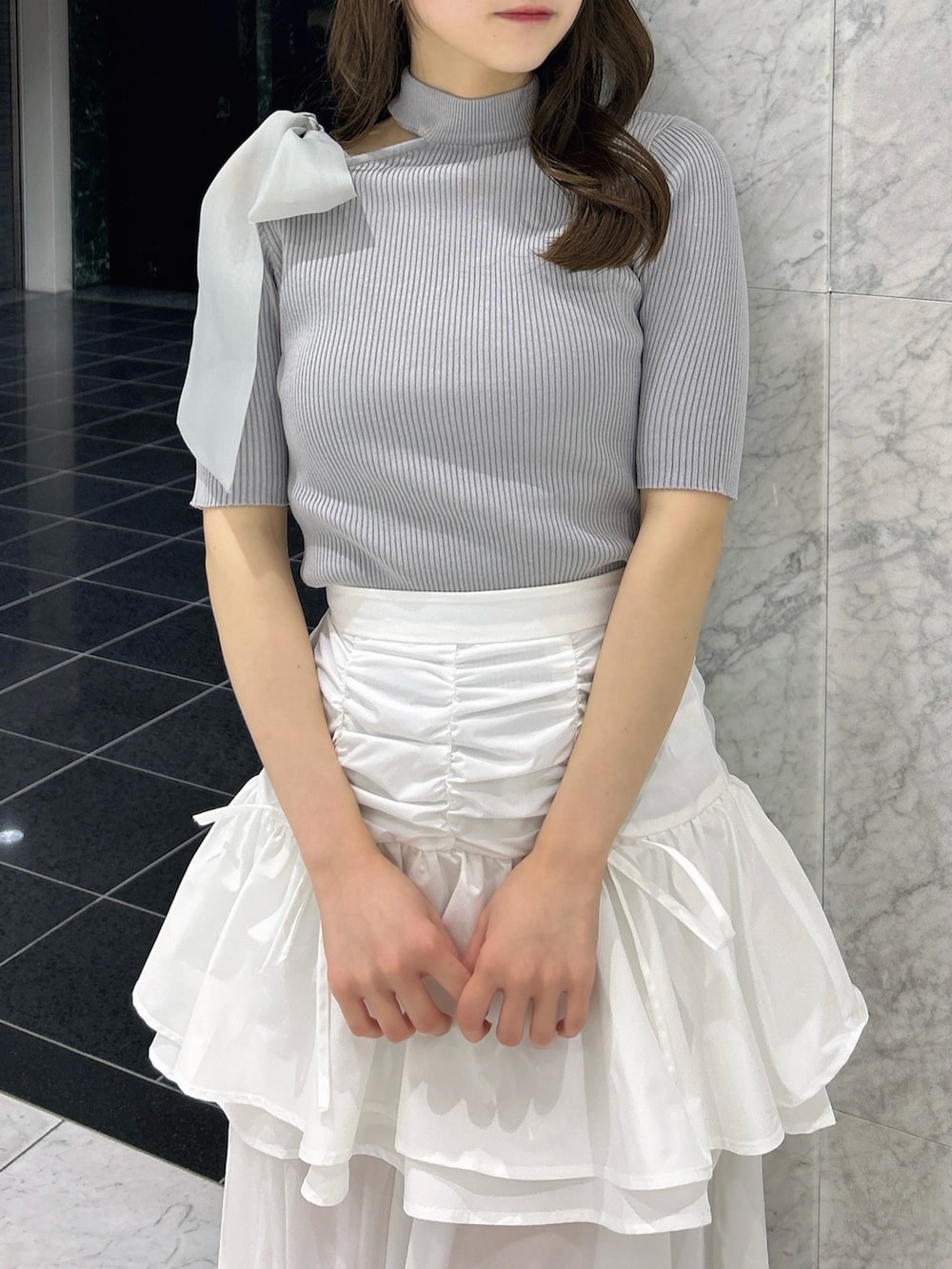 グレー系のニット/セーター、ホワイト系のスカート、ホワイト系のブーツを着用したレディースの春コーディネートの6枚目の写真