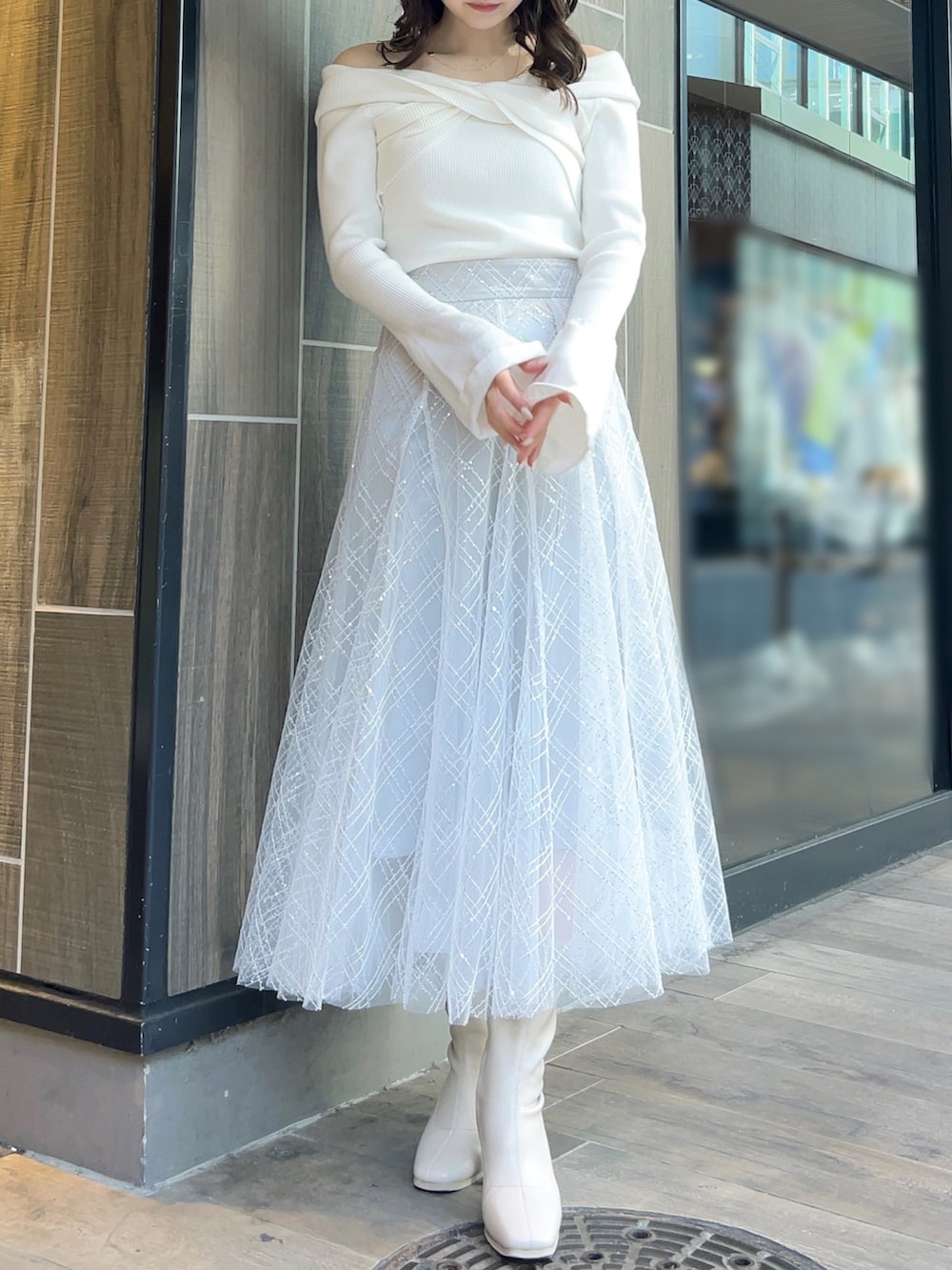 ホワイト系のニット/セーター、グレー系のスカート、ホワイト系のブーツを着用したレディースの冬コーディネートの2枚目の写真