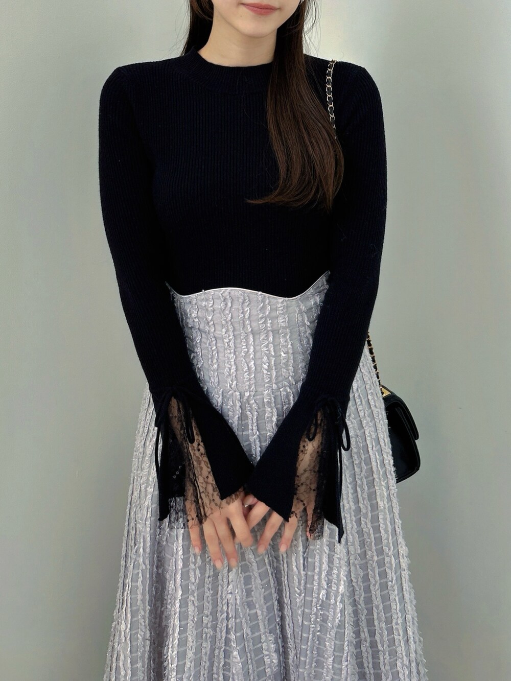 ブラック系のニット/セーター、グレー系のスカート、ブラック系のパンプスを着用したレディースの秋コーディネートの7枚目の写真