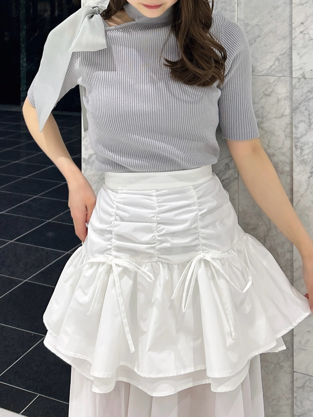 グレー系のニット/セーター、ホワイト系のスカート、ホワイト系のブーツを着用したレディースの春コーディネートの7枚目の写真