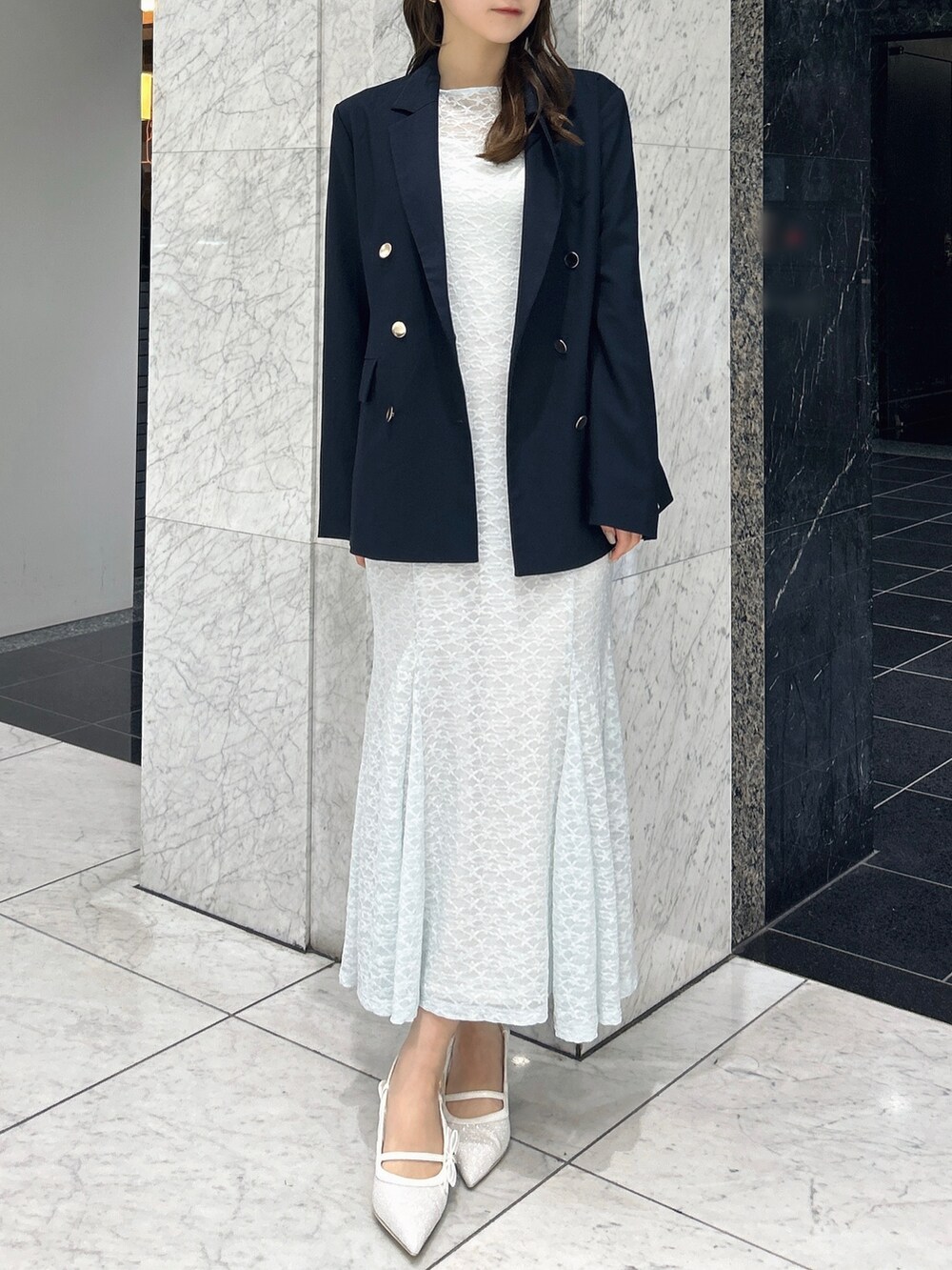 ブルー系のテーラードジャケット、ブルー系のワンピース、ホワイト系のパンプスを着用したレディースの春コーディネートの3枚目の写真