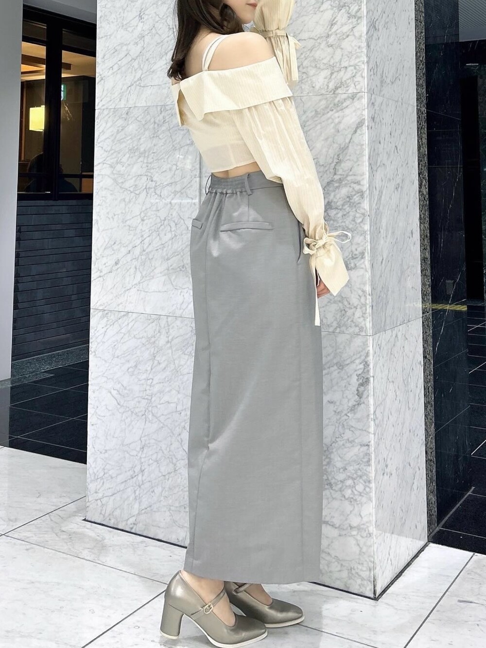 グレー系のスカート、シルバー系のパンプス、イエロー系のシャツ/ブラウスを着用したレディースの春コーディネートの5枚目の写真