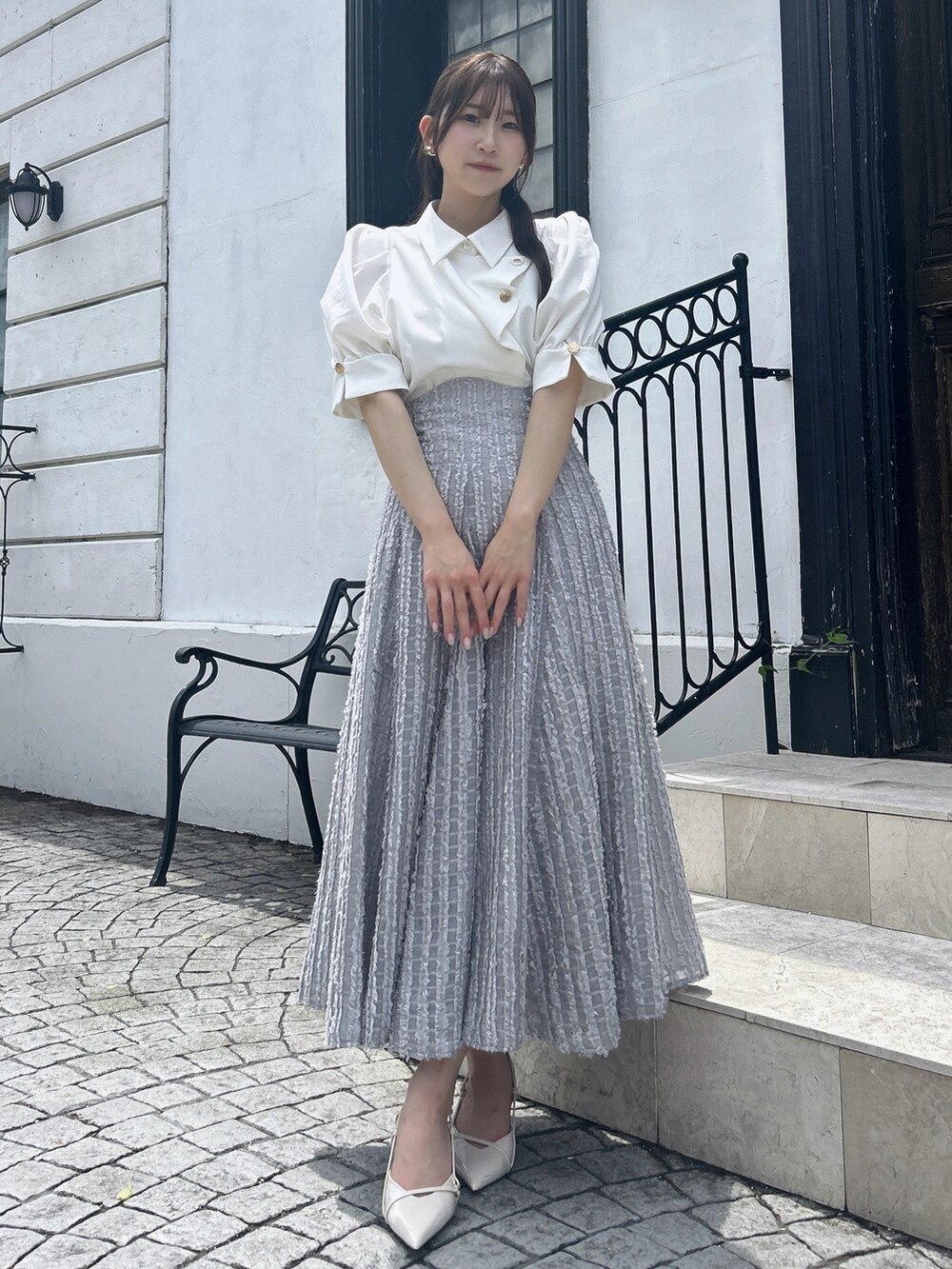 グレー系のスカート、ホワイト系のシャツ/ブラウスを着用したレディースの夏コーディネートの2枚目の写真