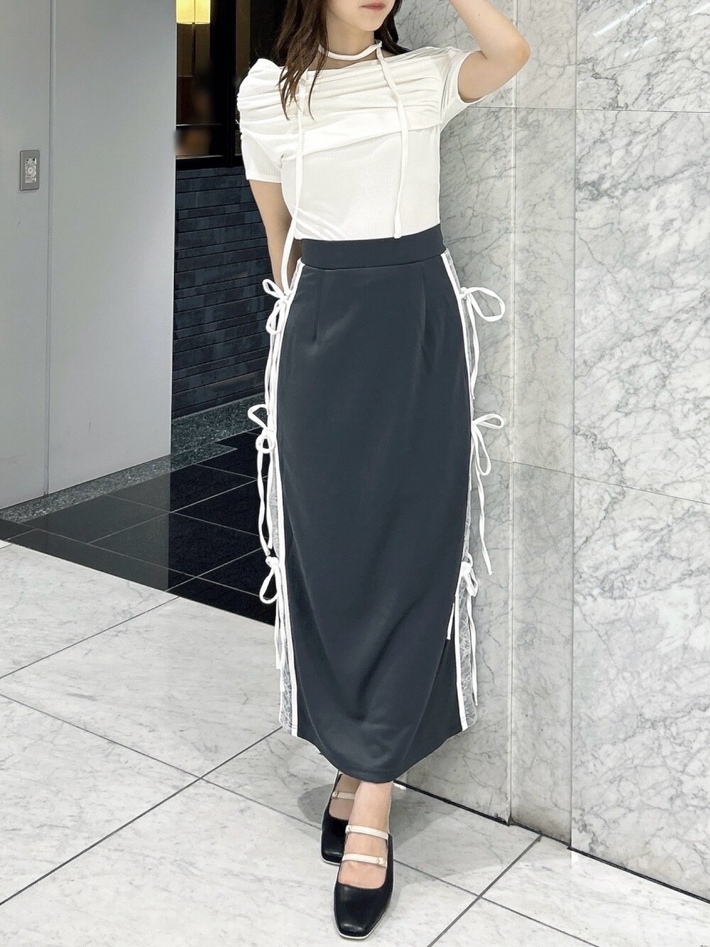 グレー系のスカート、ホワイト系のTシャツ/カットソー、ブラック系のパンプスを着用したレディースの秋コーディネートの2枚目の写真