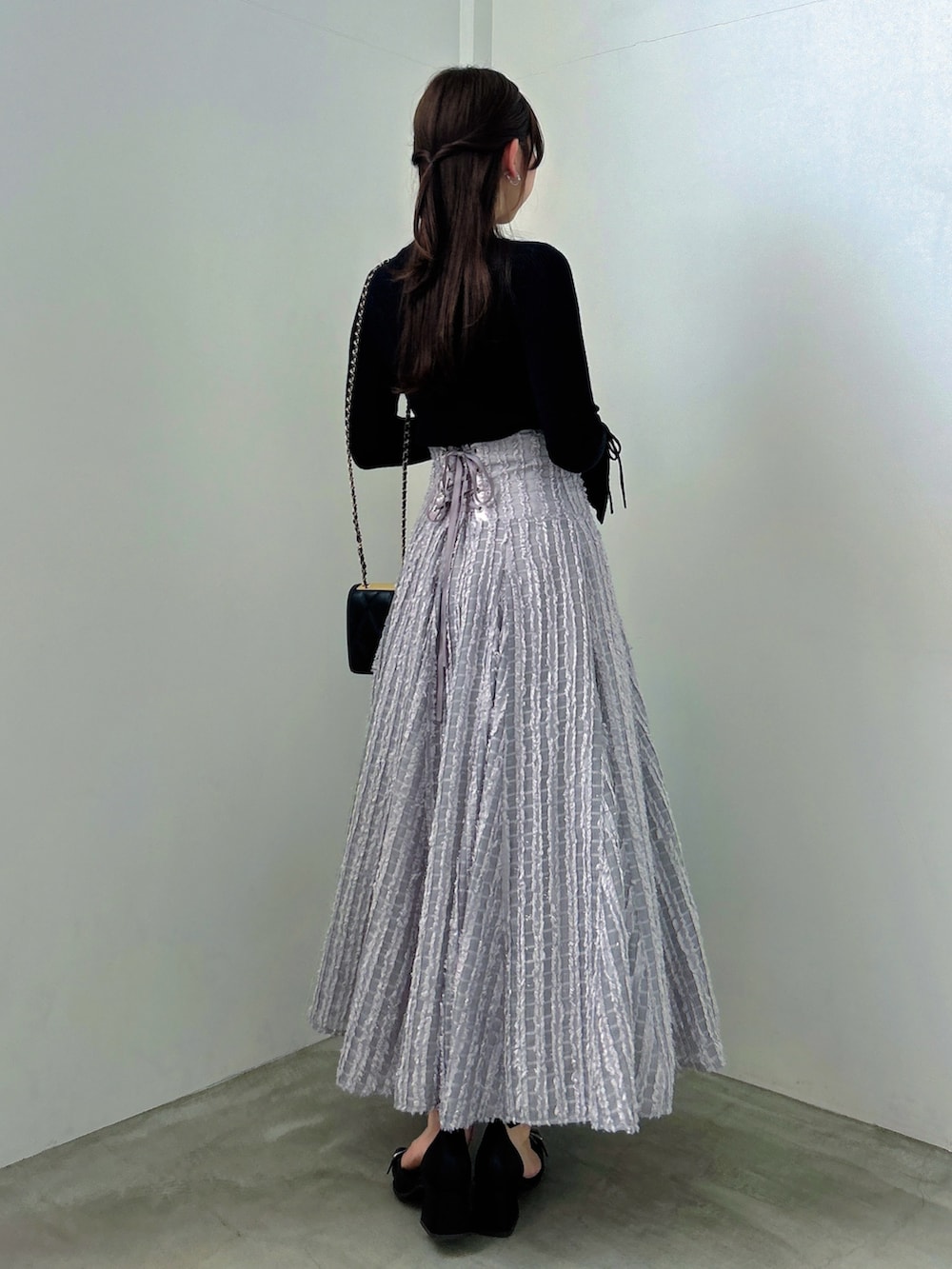 ブラック系のニット/セーター、グレー系のスカート、ブラック系のパンプスを着用したレディースの秋コーディネートの5枚目の写真