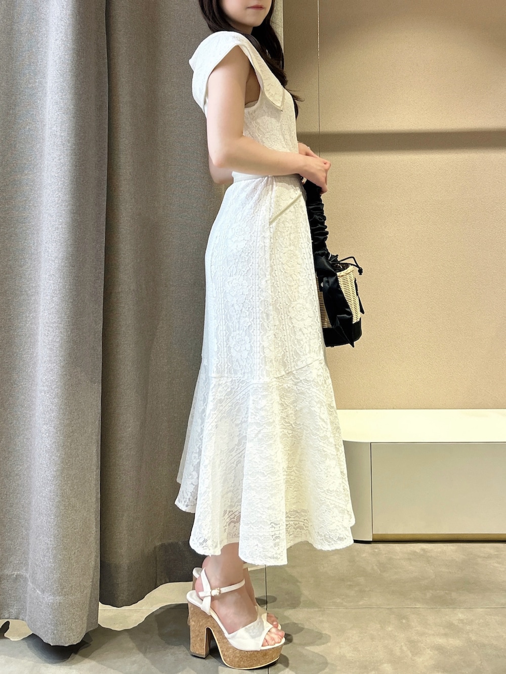 ホワイト系のワンピース、ホワイト系のサンダル、ブラック系のかごバッグを着用したレディースの夏コーディネートの4枚目の写真