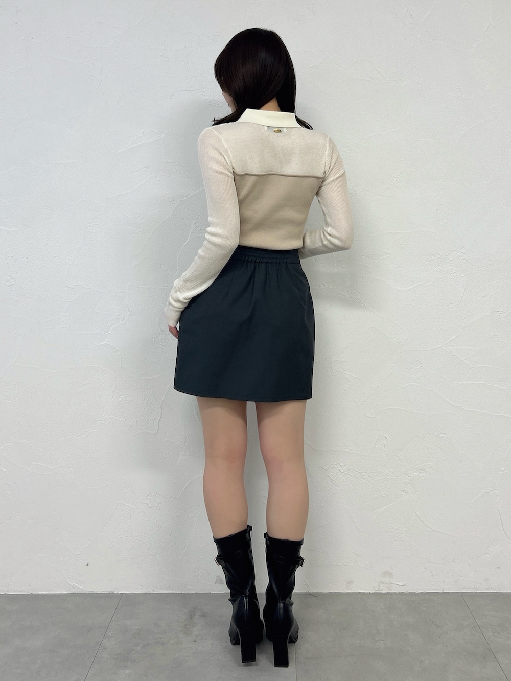 グレー系のスカート、ブラック系のブーツ、ベージュ系のニット/セーターを着用したレディースの春コーディネートの5枚目の写真