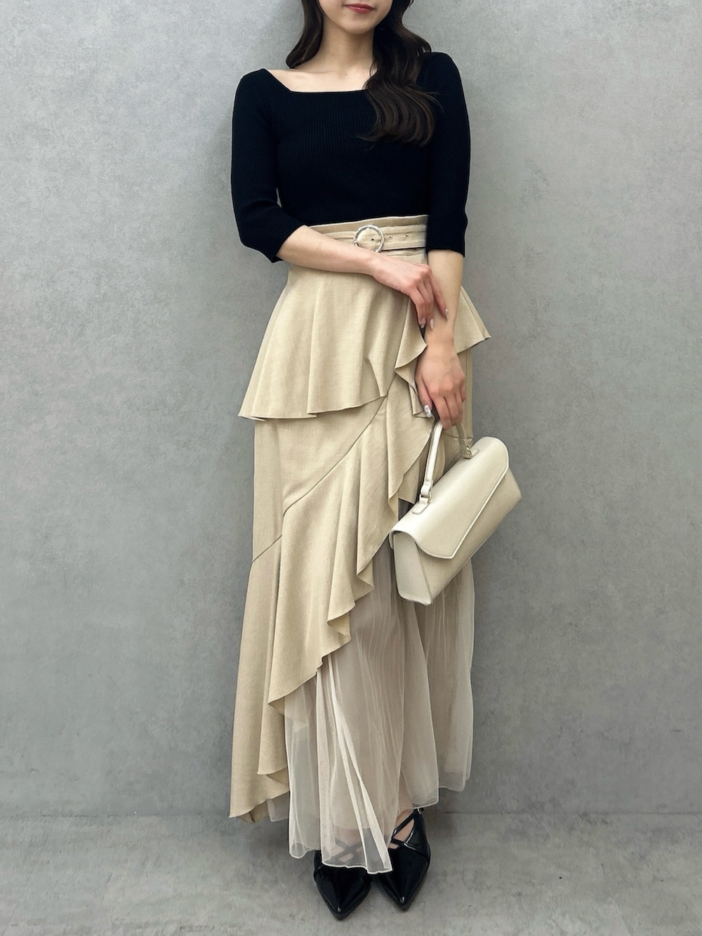 ブラック系のニット/セーター、ベージュ系のスカート、ブラック系のパンプスを着用したレディースの冬コーディネートの3枚目の写真