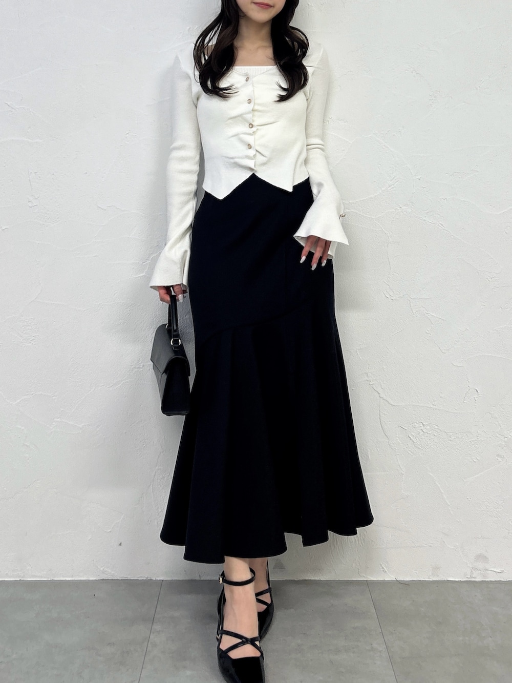 ホワイト系のニット/セーター、ブラック系のスカート、ブラック系のサンダルを着用したレディースの春コーディネートの2枚目の写真