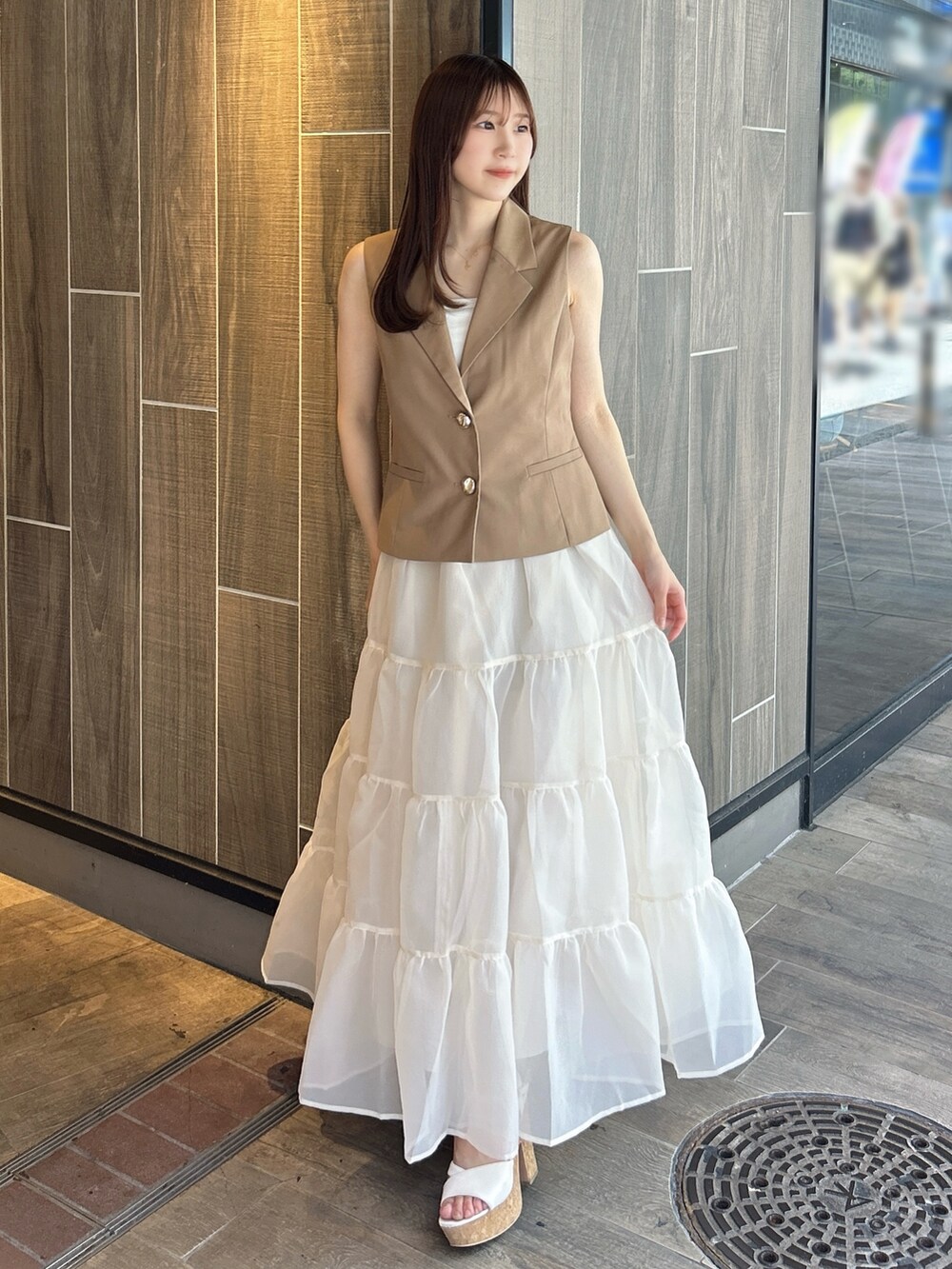 ブラウン系のベスト、ホワイト系のTシャツ/カットソー、ベージュ系のスカートを着用したレディースの秋コーディネートの2枚目の写真