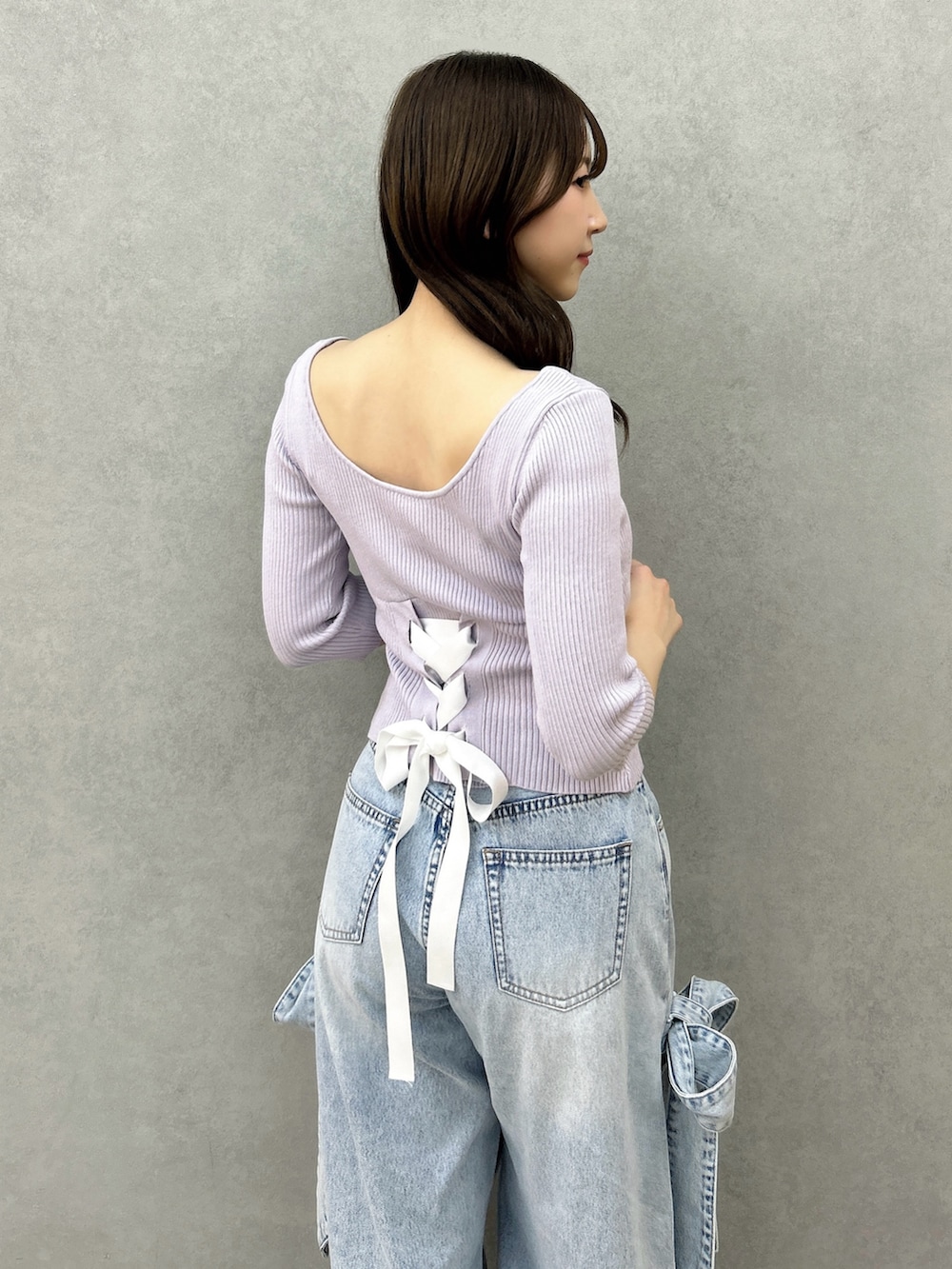 パープル系のニット/セーター、ブルー系のデニムパンツ、ホワイト系のパンプスを着用したレディースの冬コーディネートの9枚目の写真