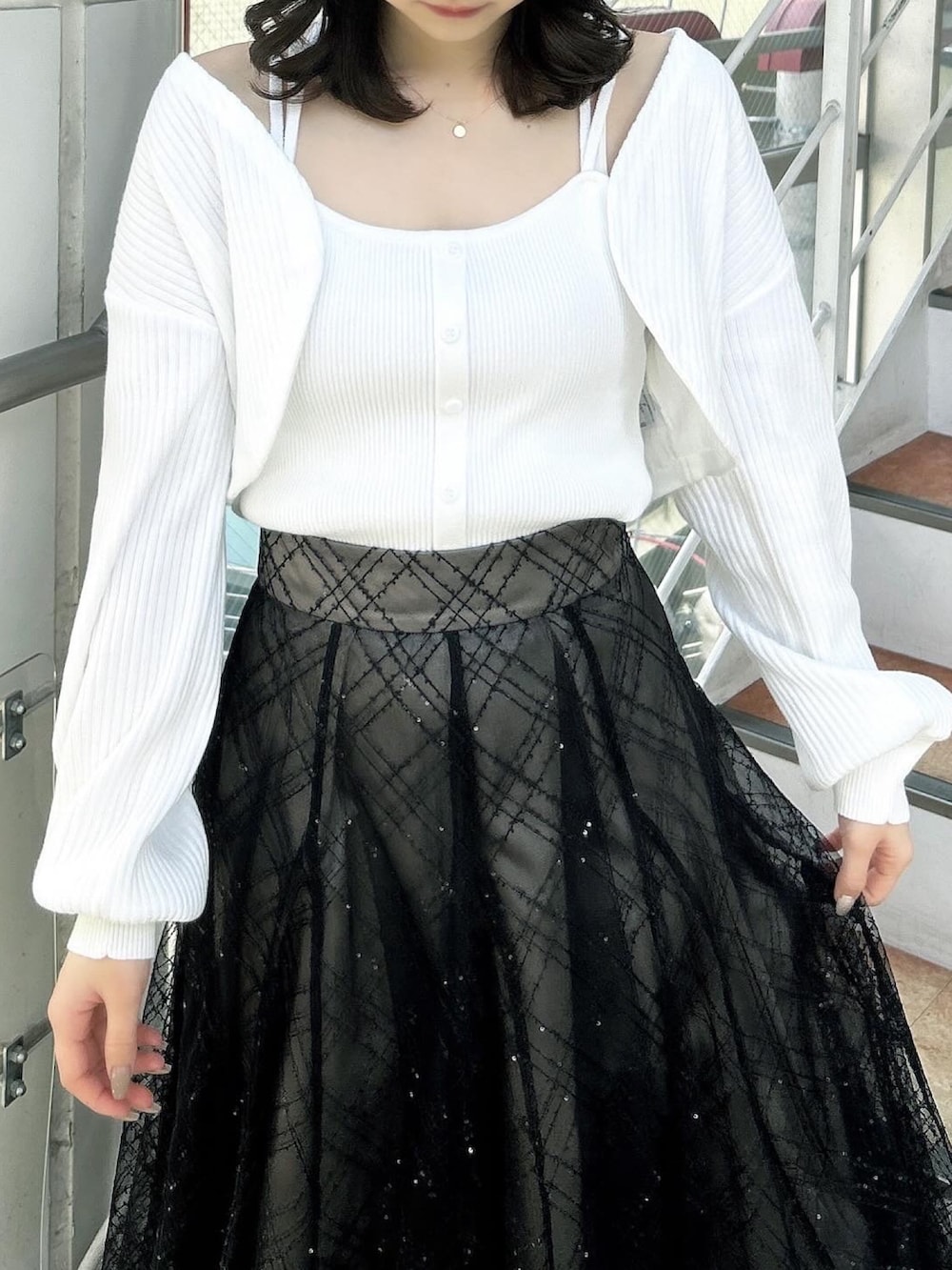 ホワイト系のアンサンブル、ブラック系のスカート、ブラック系のパンプスを着用したレディースの春コーディネートの10枚目の写真