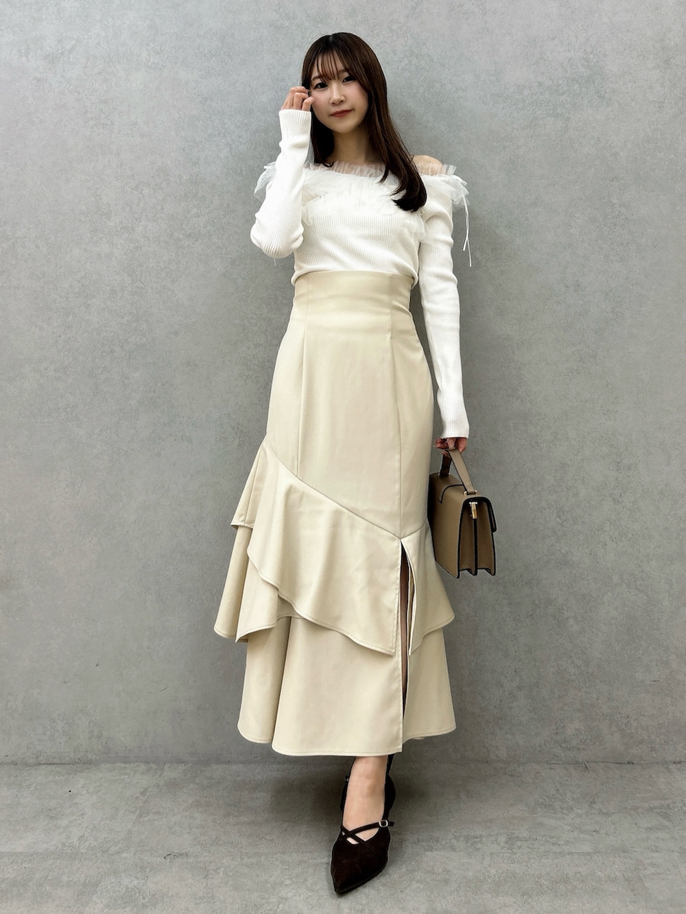 ホワイト系のニット/セーター、ホワイト系のスカート、ブラウン系のパンプスを着用したレディースの秋コーディネートの2枚目の写真