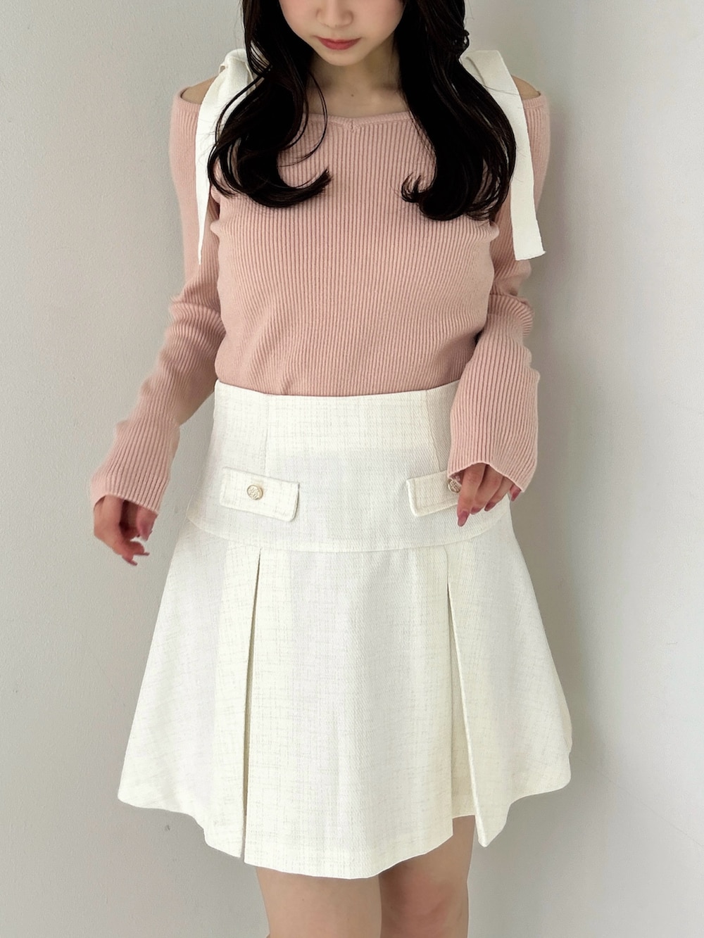 ピンク系のニット/セーター、ホワイト系のスカート、ホワイト系のブーツを着用したレディースの冬コーディネートの7枚目の写真