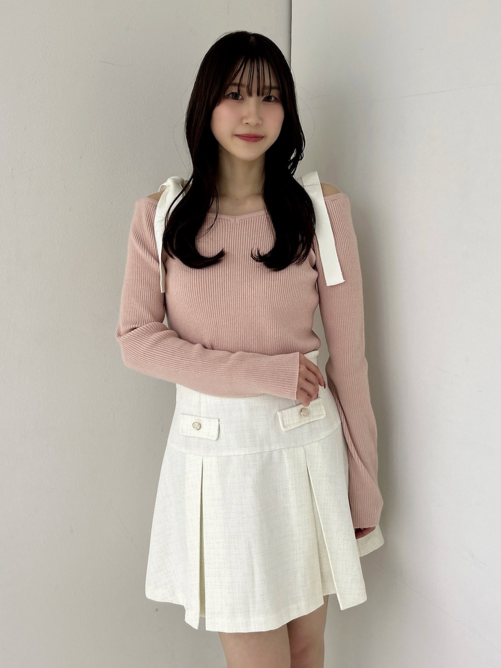 ピンク系のニット/セーター、ホワイト系のスカート、ホワイト系のブーツを着用したレディースの冬コーディネートの8枚目の写真