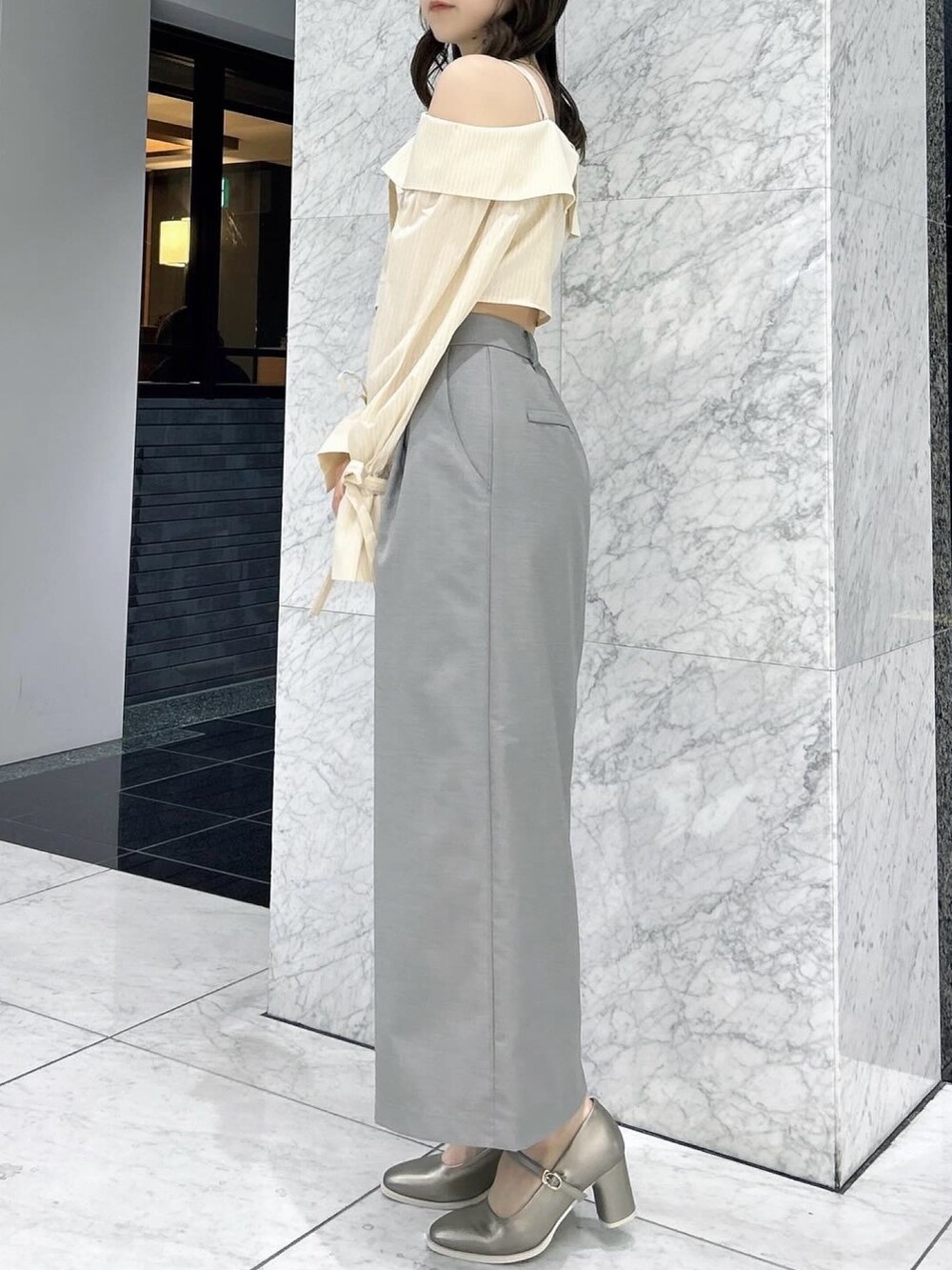 グレー系のスカート、シルバー系のパンプス、イエロー系のシャツ/ブラウスを着用したレディースの春コーディネートの3枚目の写真