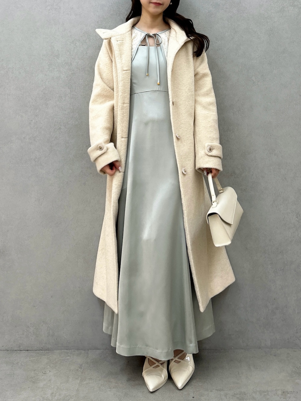 ホワイト系のその他アウター、グリーン系のドレス、ホワイト系のパンプスを着用したレディースの冬コーディネートの2枚目の写真