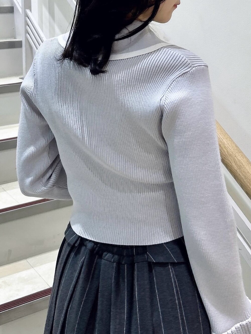 グレー系のニット/セーター、グレー系のスカート、ブラック系のブーツを着用したレディースの冬コーディネートの10枚目の写真