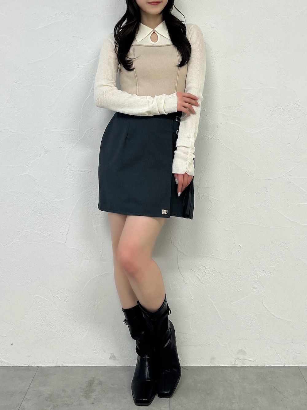 グレー系のスカート、ブラック系のブーツ、ベージュ系のニット/セーターを着用したレディースの春コーディネートの4枚目の写真
