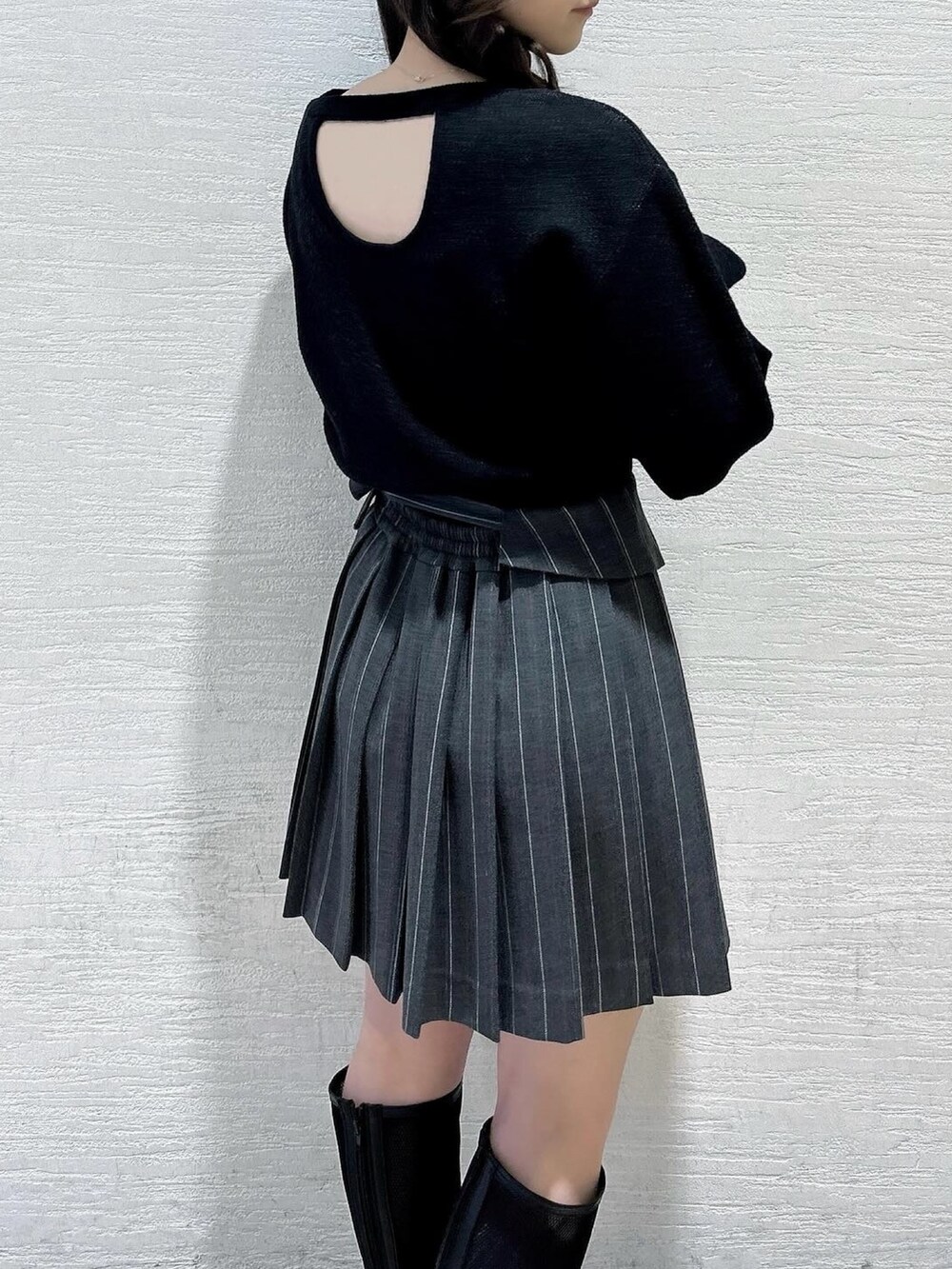 ブラック系のニット/セーター、グレー系のスカート、ブラック系のブーツを着用したレディースの春コーディネートの7枚目の写真