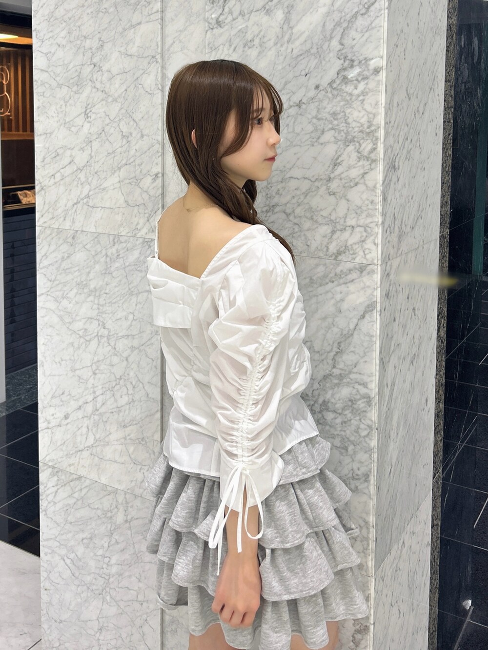 グレー系のスカート、ブルー系のハンドバッグ、ベージュ系のブーツを着用したレディースの春コーディネートの10枚目の写真