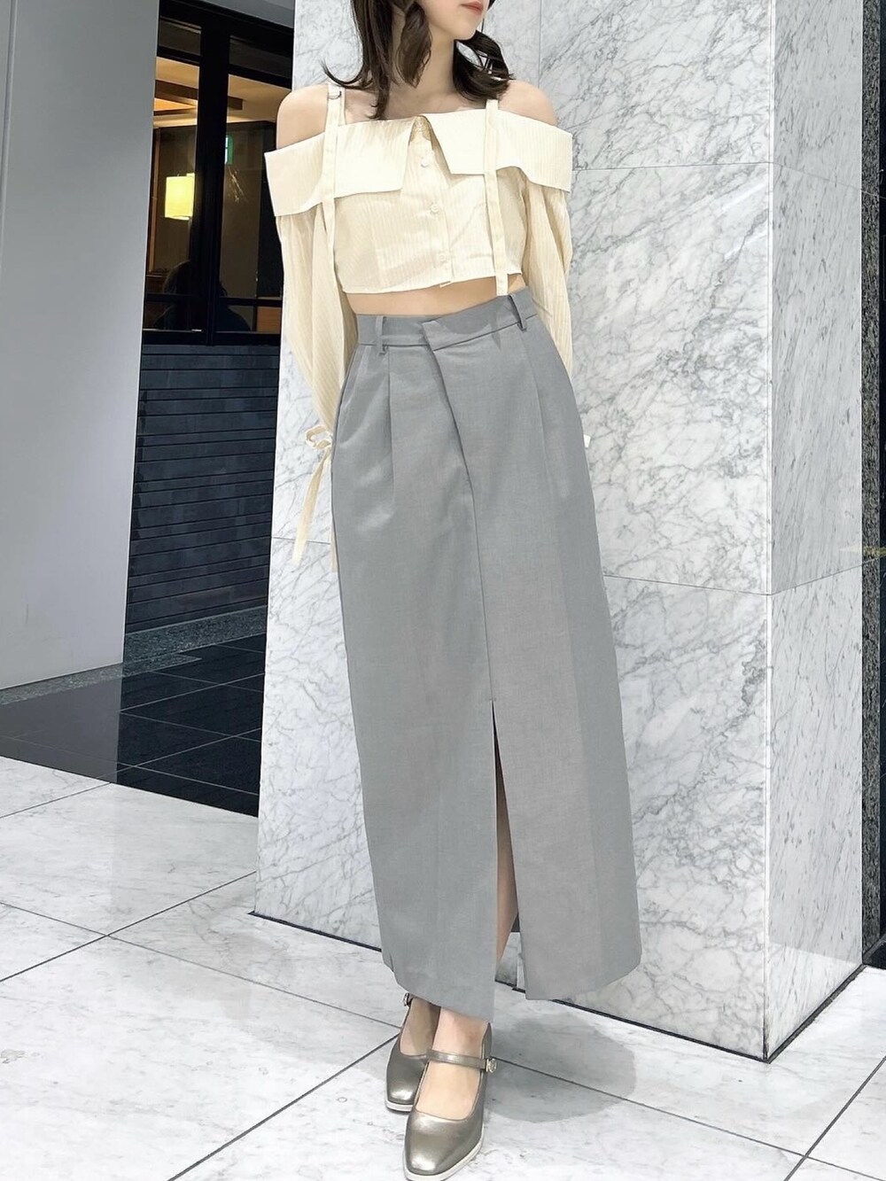 グレー系のスカート、シルバー系のパンプス、イエロー系のシャツ/ブラウスを着用したレディースの春コーディネートの2枚目の写真