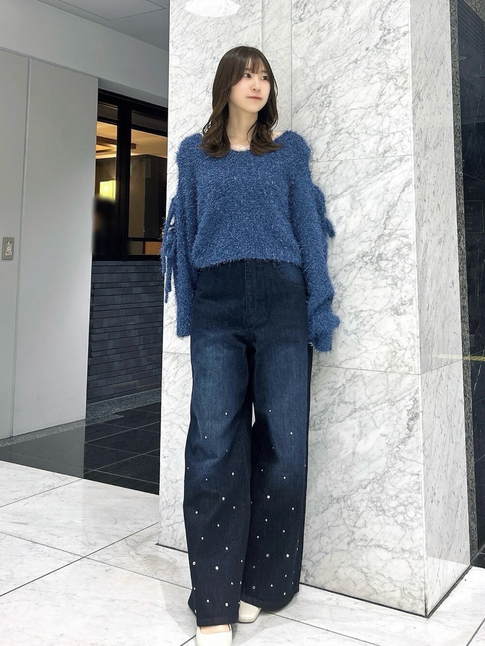 ブルー系のニット/セーター、ブルー系のデニムパンツ、ホワイト系のパンプスを着用したレディースの夏コーディネートの4枚目の写真