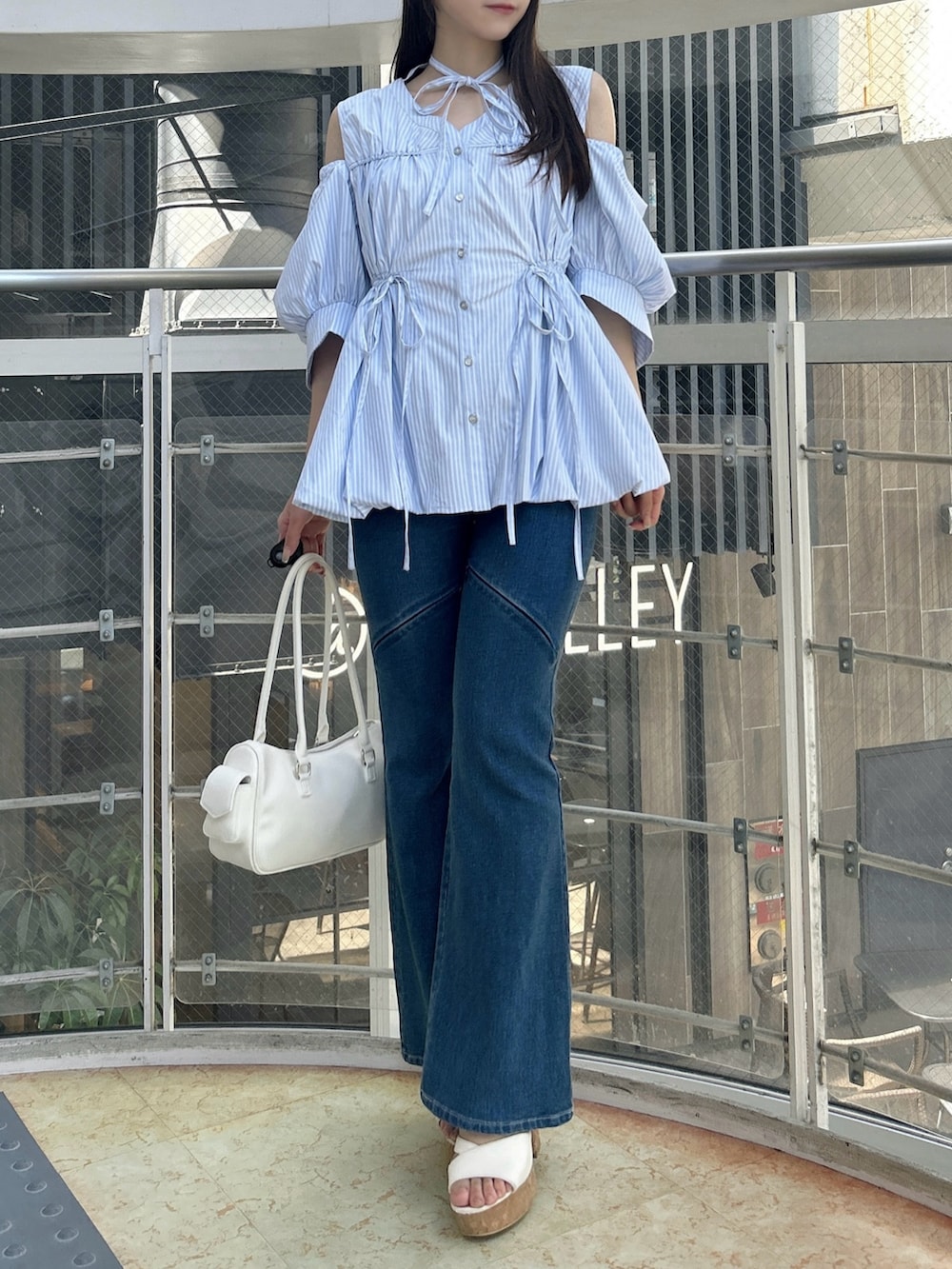 ブルー系のシャツ/ブラウス、ブルー系のデニムパンツ、ホワイト系のサンダルを着用したレディースの秋コーディネートの2枚目の写真