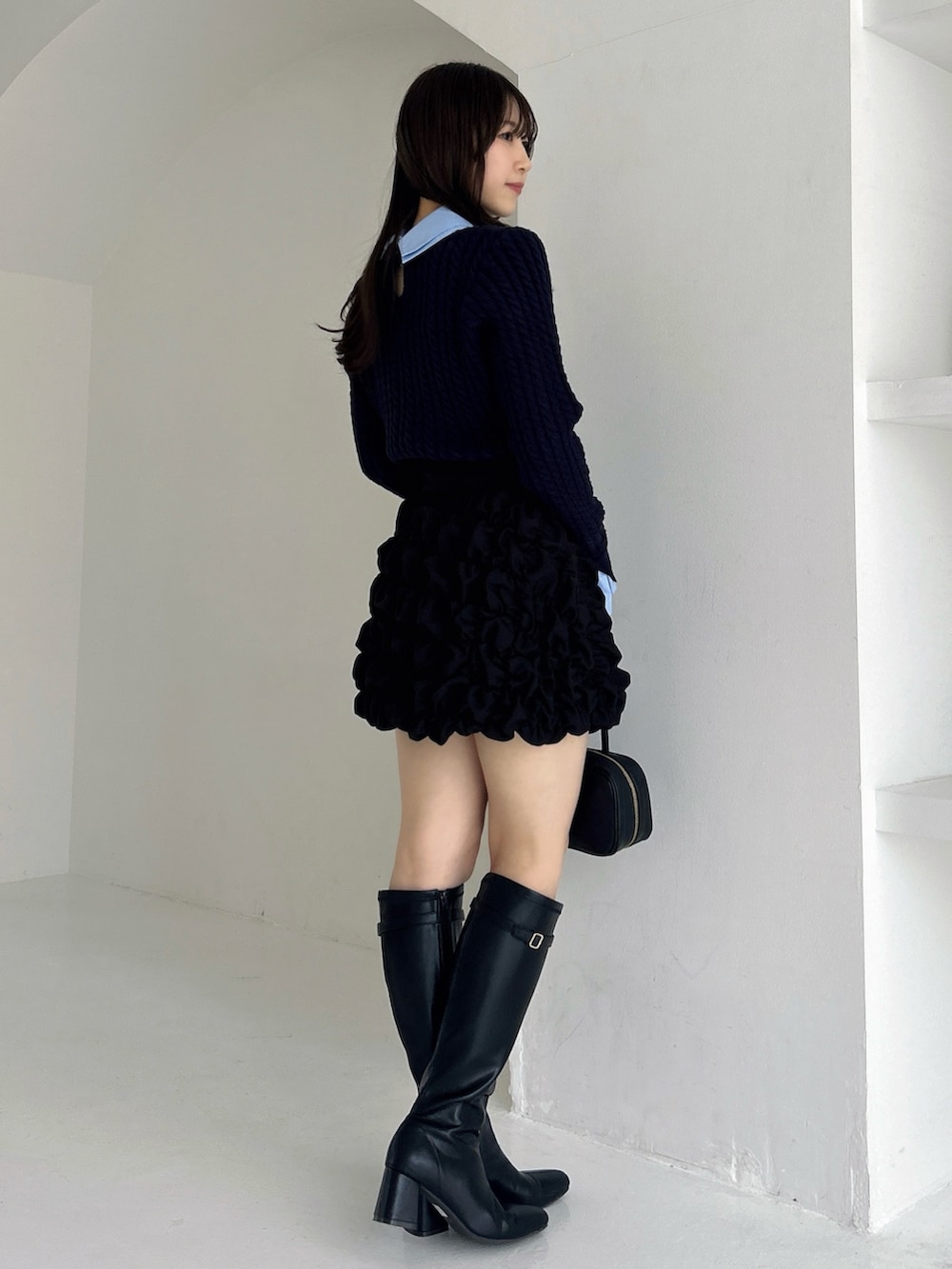 ブラック系のブーツ、ブラック系のスカート、ブルー系のニット/セーターを着用したレディースの冬コーディネートの5枚目の写真