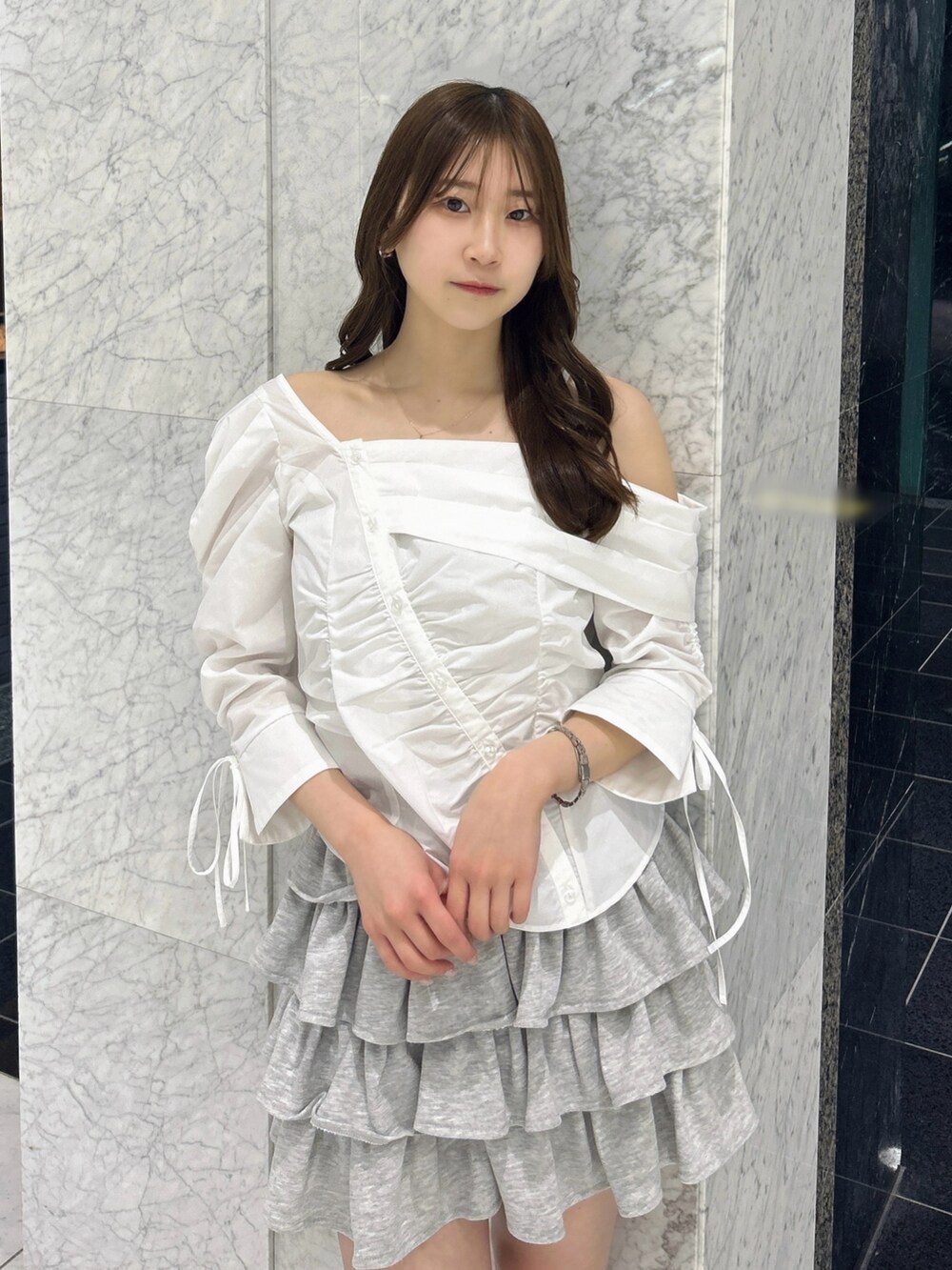 グレー系のスカート、ブルー系のハンドバッグ、ベージュ系のブーツを着用したレディースの春コーディネートの6枚目の写真