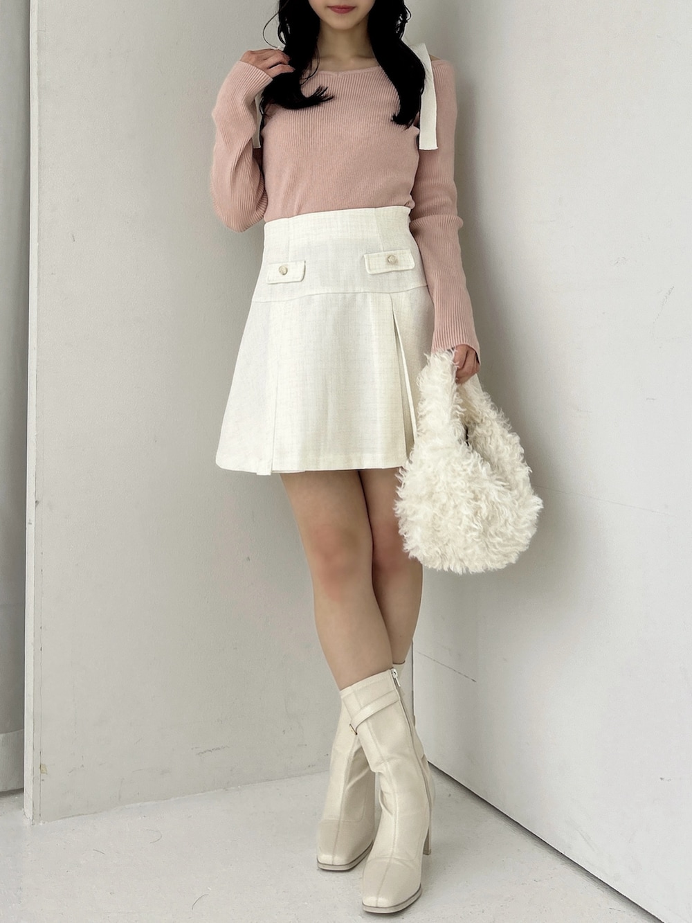 ピンク系のニット/セーター、ホワイト系のスカート、ホワイト系のブーツを着用したレディースの冬コーディネートの4枚目の写真