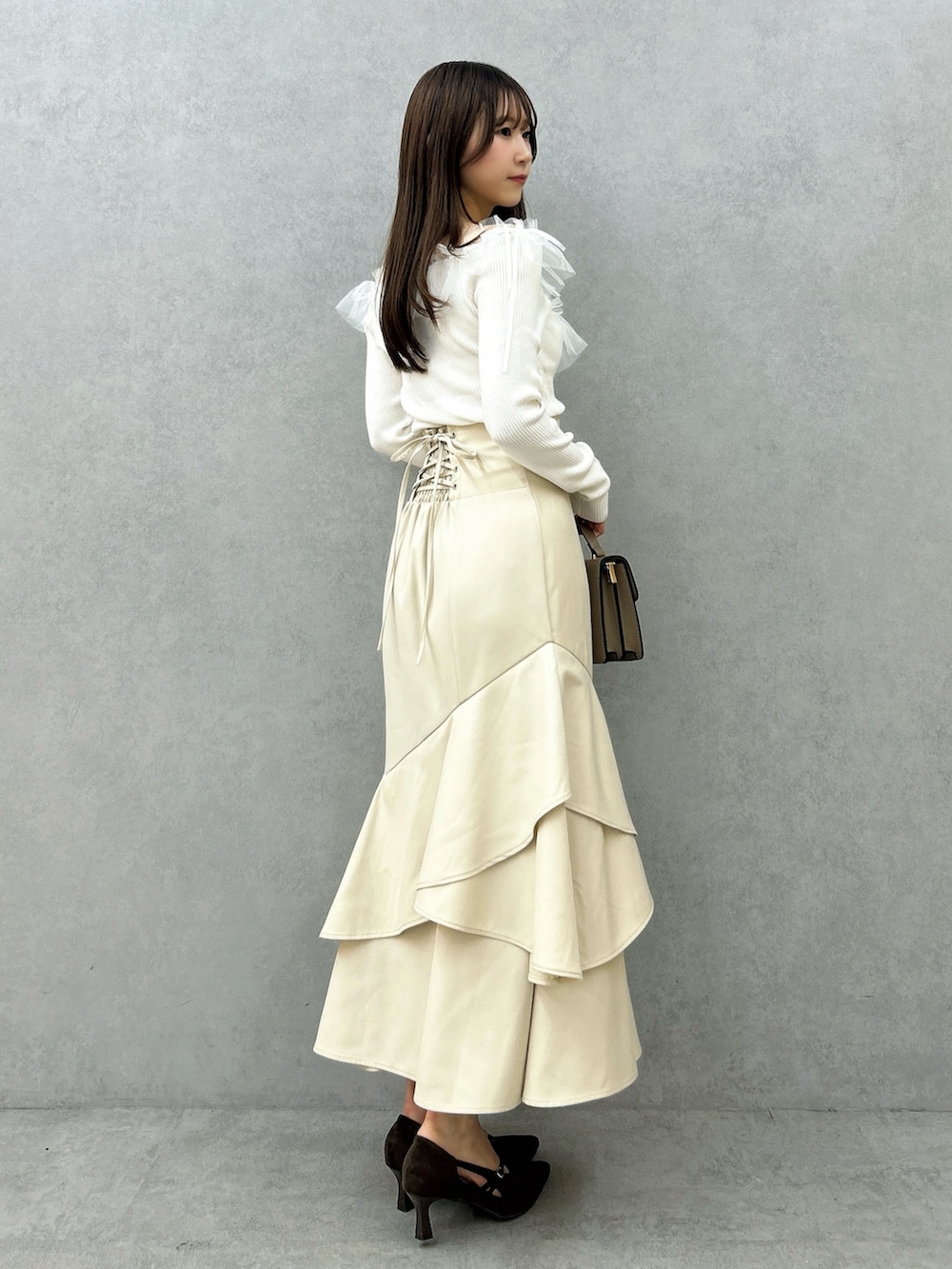 ホワイト系のニット/セーター、ホワイト系のスカート、ブラウン系のパンプスを着用したレディースの秋コーディネートの6枚目の写真