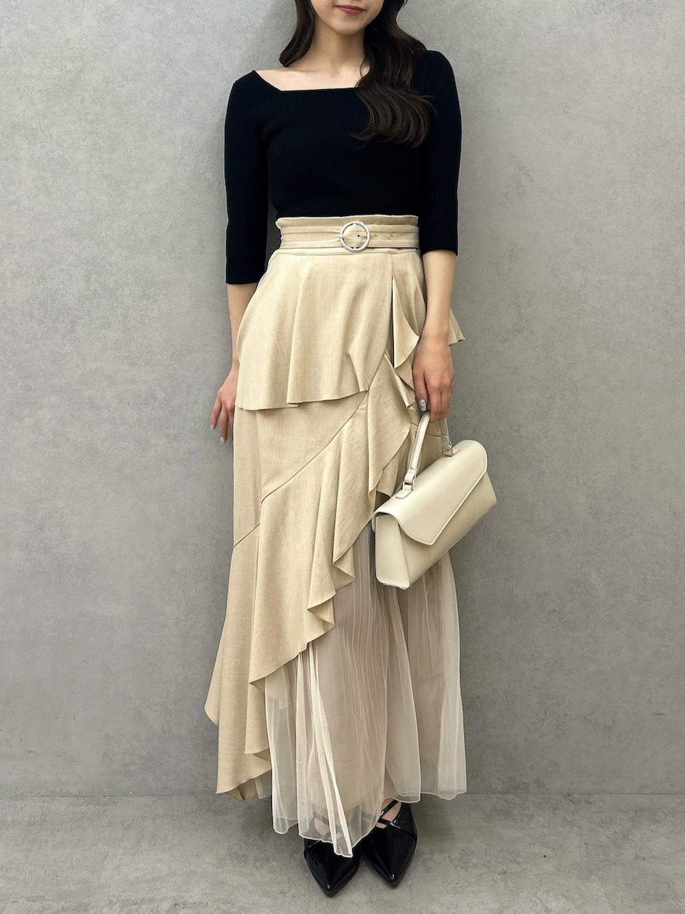 ブラック系のニット/セーター、ベージュ系のスカート、ブラック系のパンプスを着用したレディースの冬コーディネートの4枚目の写真