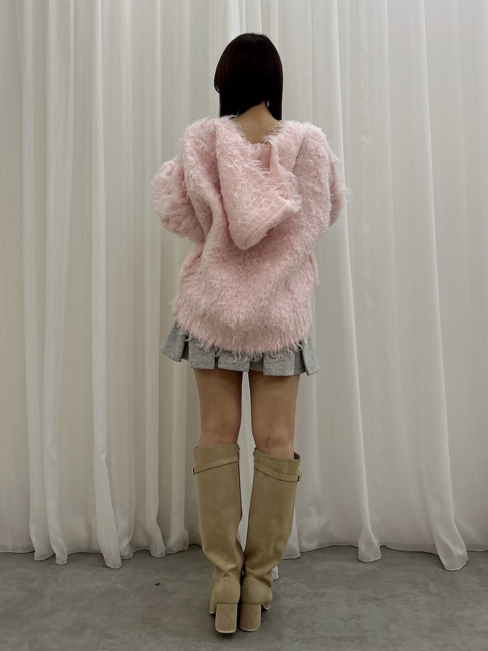 ピンク系のニット/セーター、グレー系のスカート、ホワイト系のブーツを着用したレディースの秋コーディネートの4枚目の写真