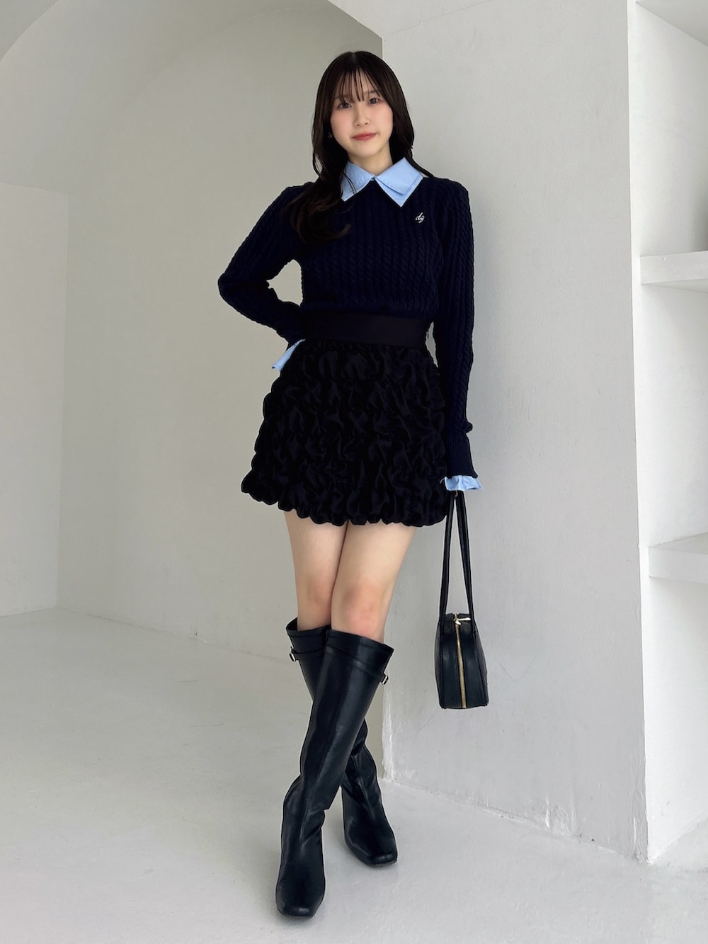 ブラック系のブーツ、ブラック系のスカート、ブルー系のニット/セーターを着用したレディースの冬コーディネートの3枚目の写真