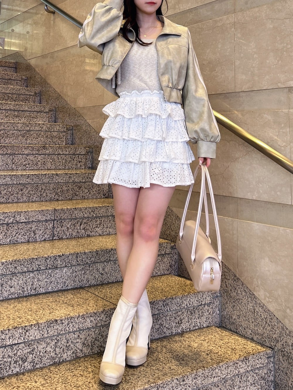 グレー系のブルゾン、ベージュ系のキャミソール、ホワイト系のスカートを着用したレディースの春コーディネートの3枚目の写真