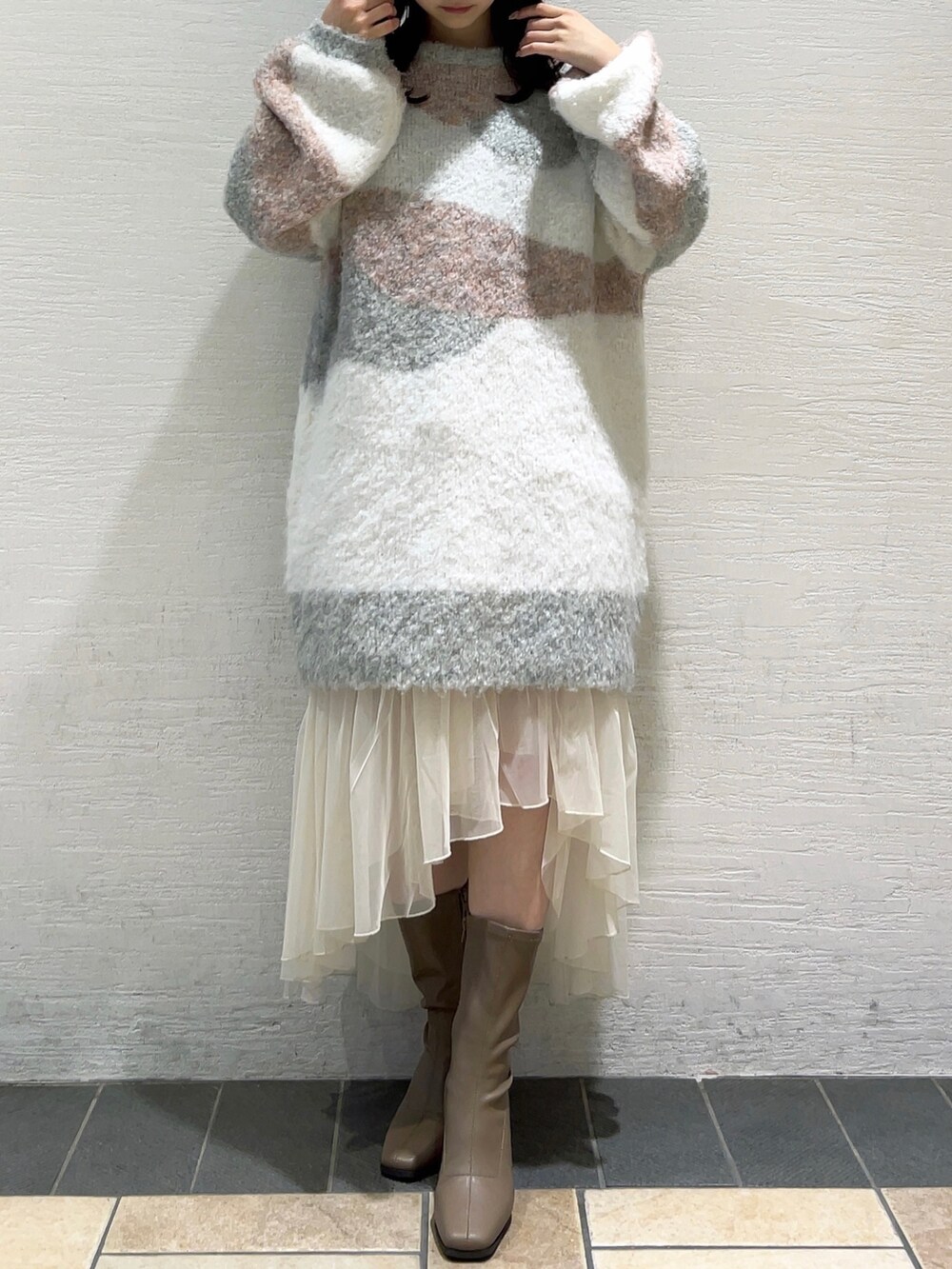 ピンク系のニット/セーター、ホワイト系のスカート、ベージュ系のブーツを着用したレディースの冬コーディネートの2枚目の写真