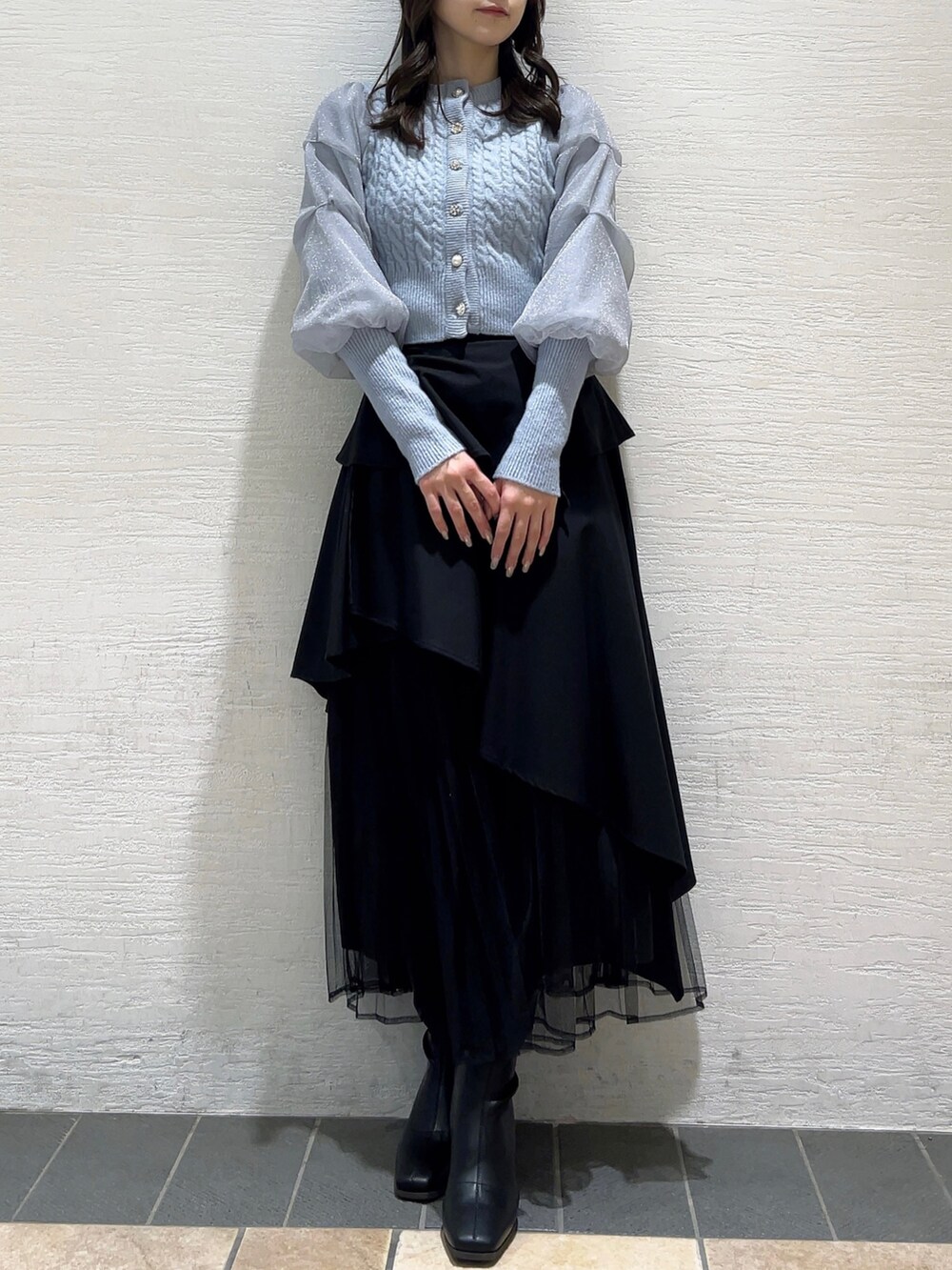 ブルー系のカーディガン/ボレロ、ブラック系のスカート、ブラック系のブーツを着用したレディースの冬コーディネートの2枚目の写真