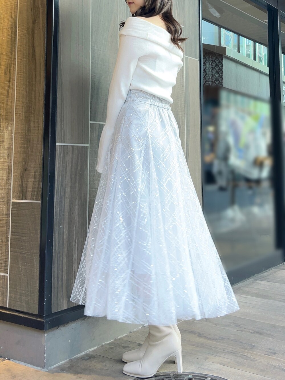 ホワイト系のニット/セーター、グレー系のスカート、ホワイト系のブーツを着用したレディースの冬コーディネートの5枚目の写真